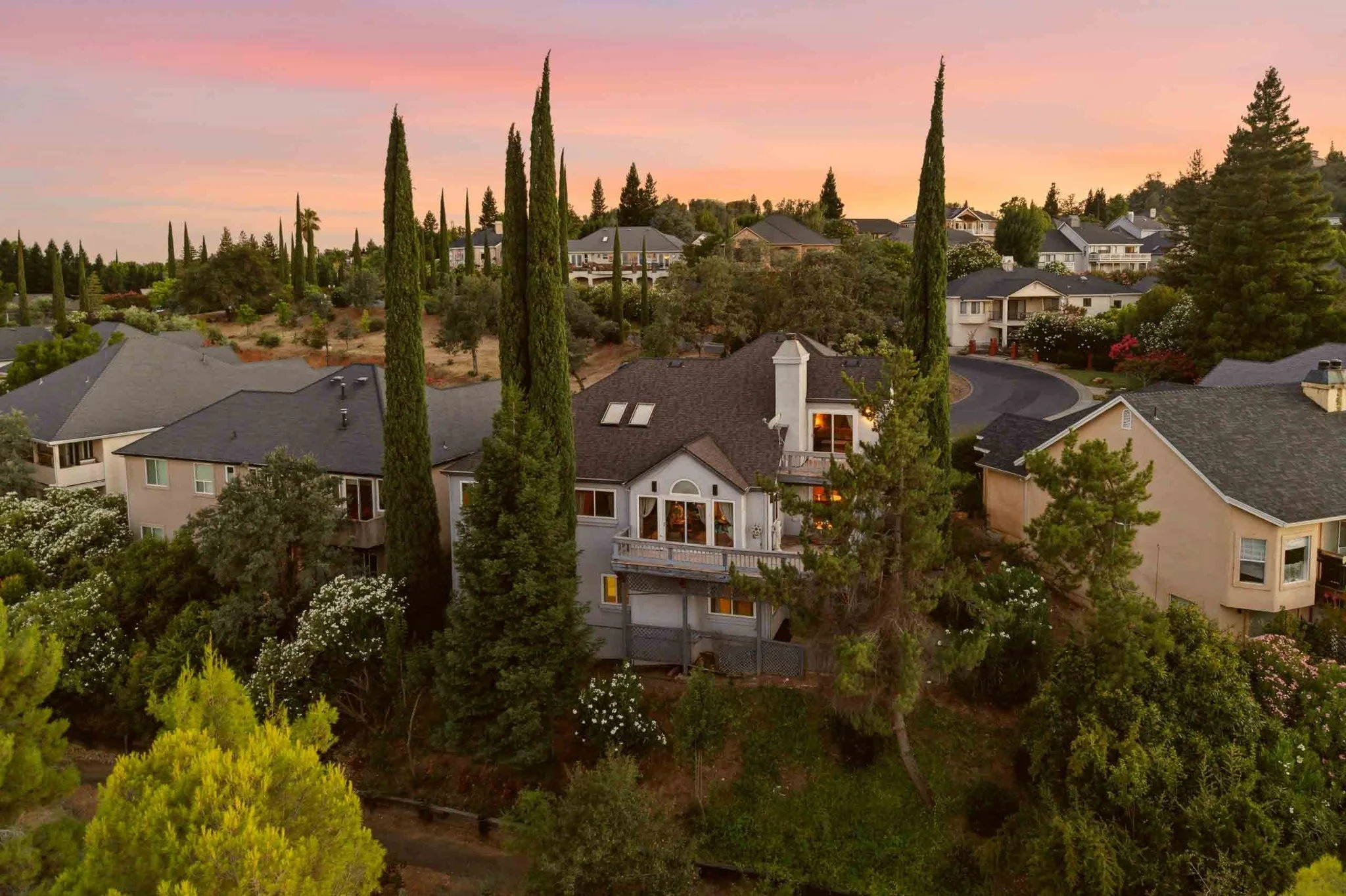 Rear aerial view of a hillside home at sunset in Redding, California.
