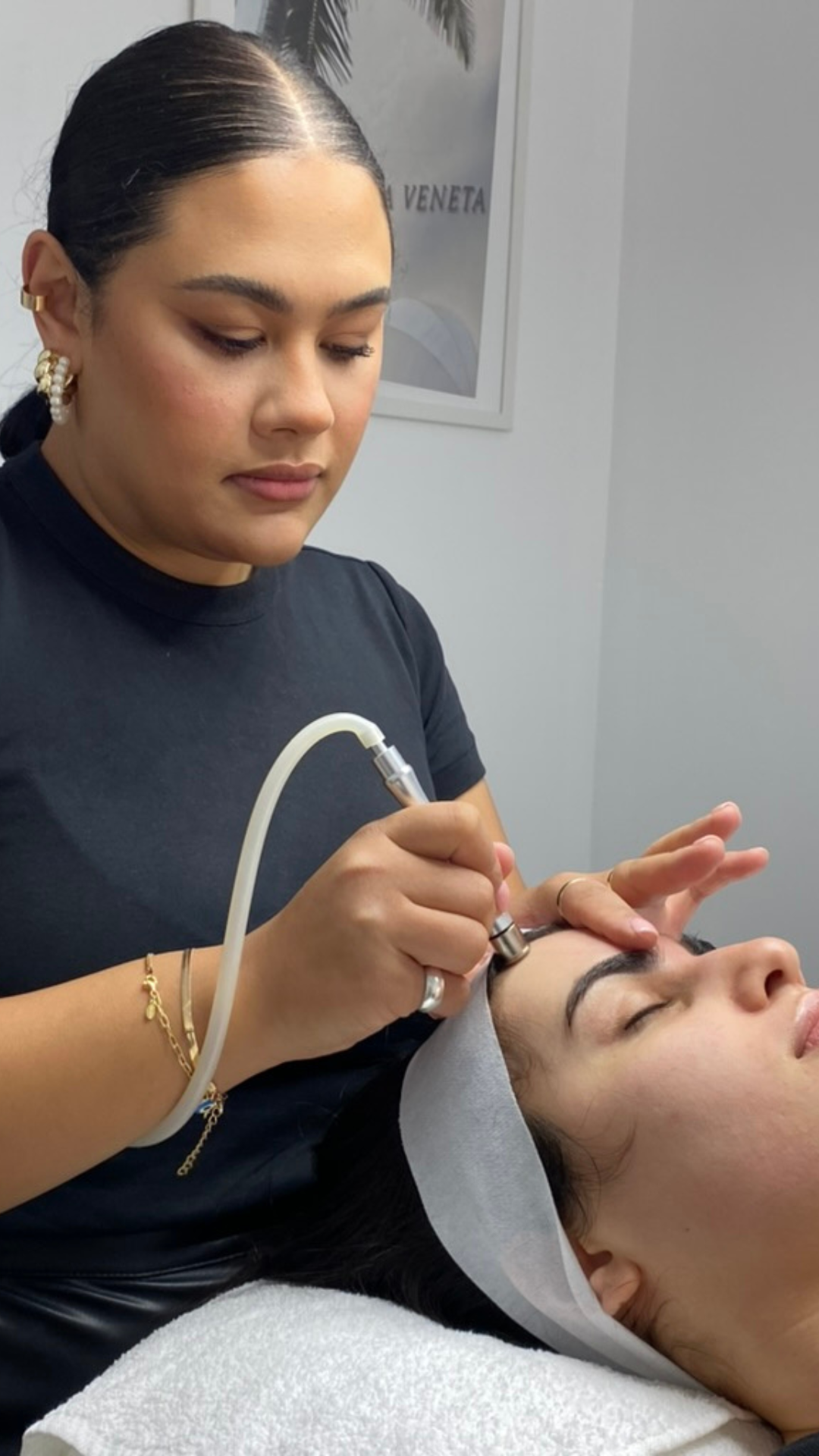 Aesthetician performing a skincare treatment on a woman's face in a spa setting.
