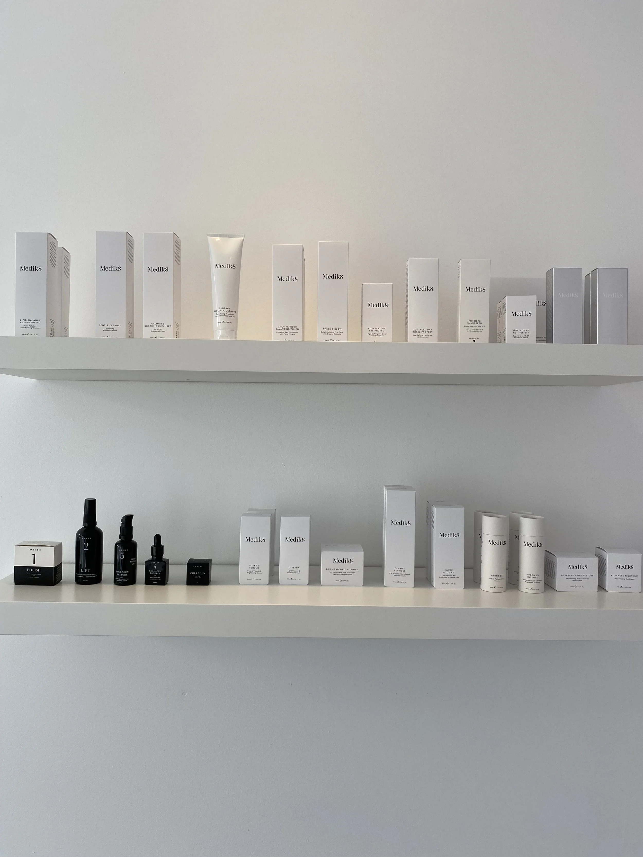 Two shelves displaying various Medik8 skincare products in black and white packaging.