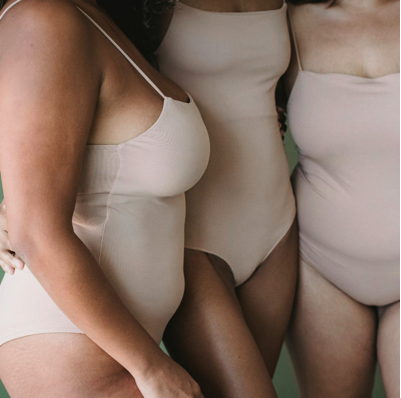 Drei Frauen unterschiedlicher Körperformen in nudefarbenen Bodys – Fokus auf Body Positivity, Gewebebeschaffenheit und die Realität des weiblichen Körpers im Postpartum.