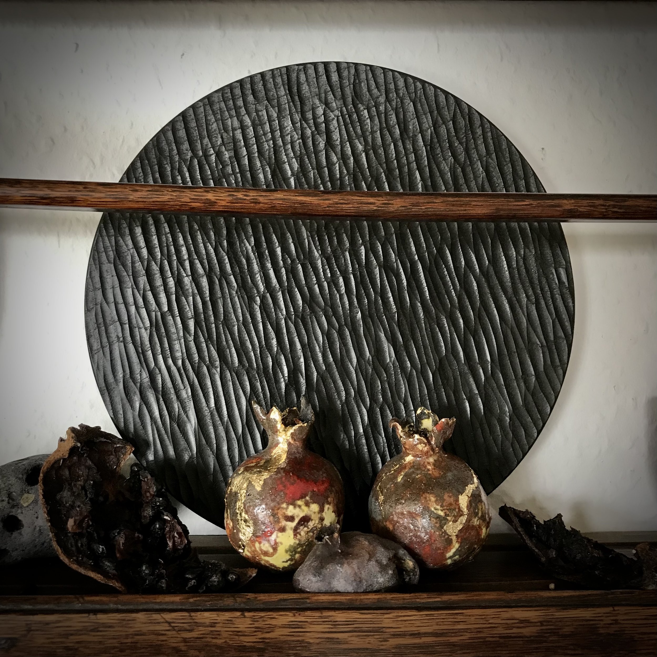 Chard Remains: black clay pomegranates, glazed and gilded, beside the chard remains of organic pomegranate husks.