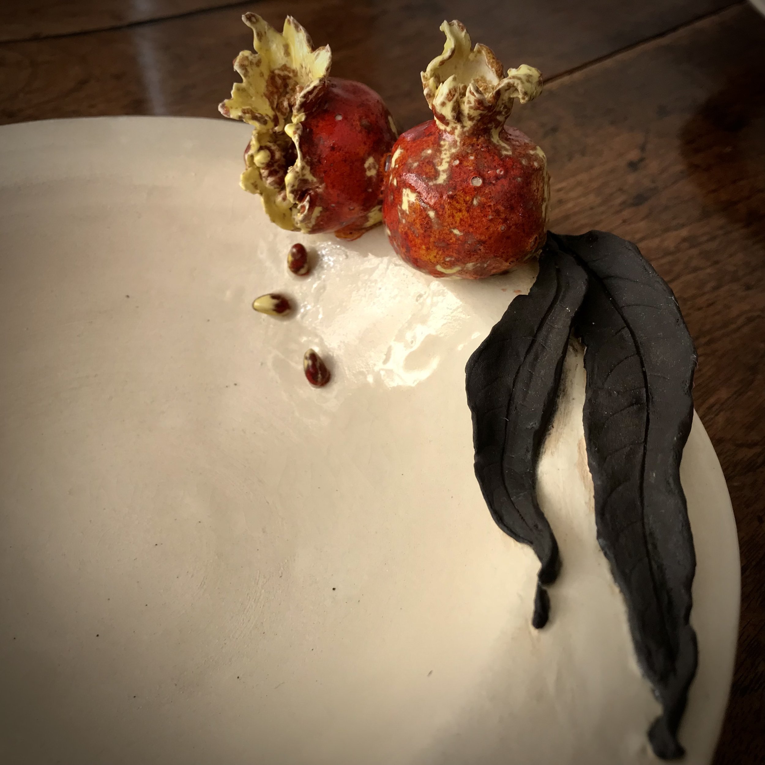 Volcanic Victuals: detail from a stoneware bowl with black powder painted leaves and glazed pomegranates.