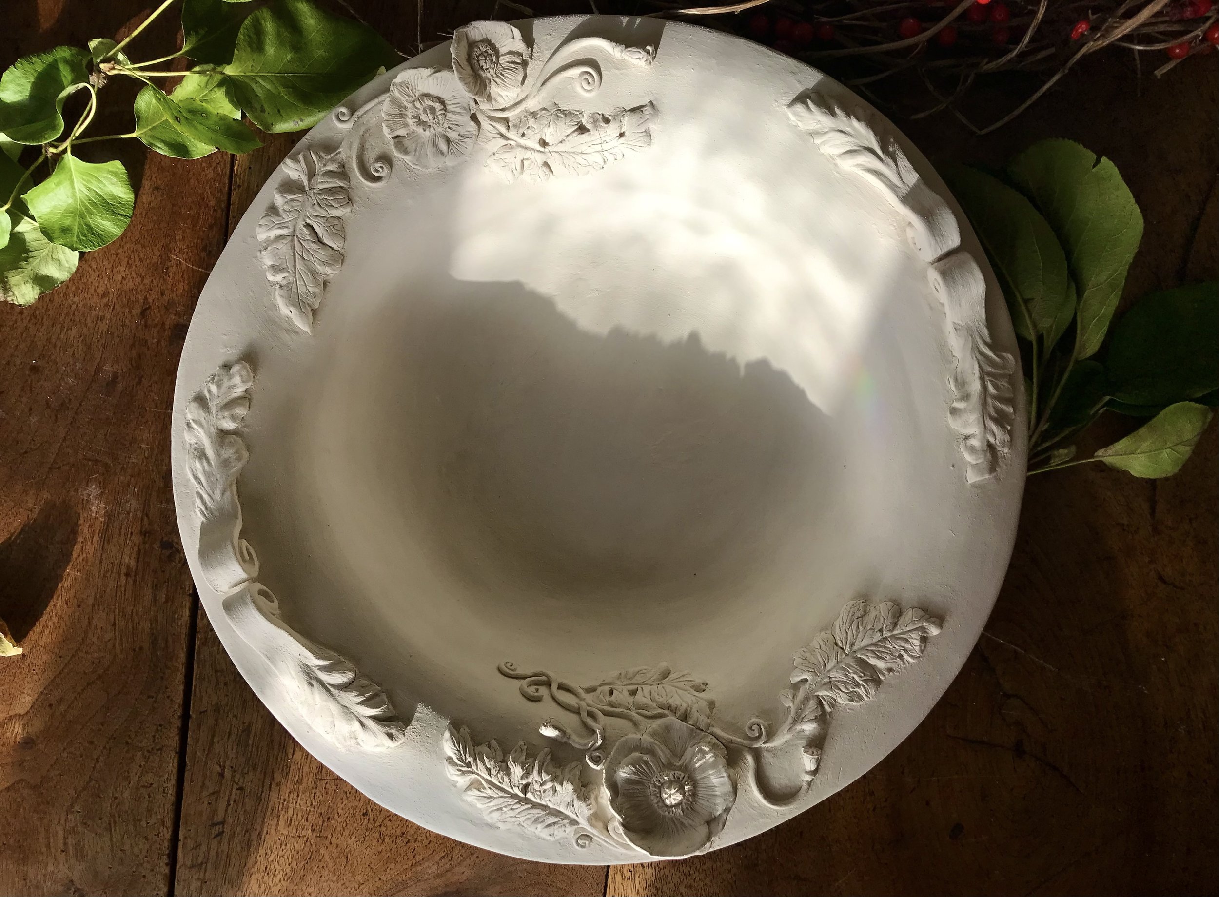 Bare biscuit ware: the platter as a plain sculpted piece before decoration and glazing.