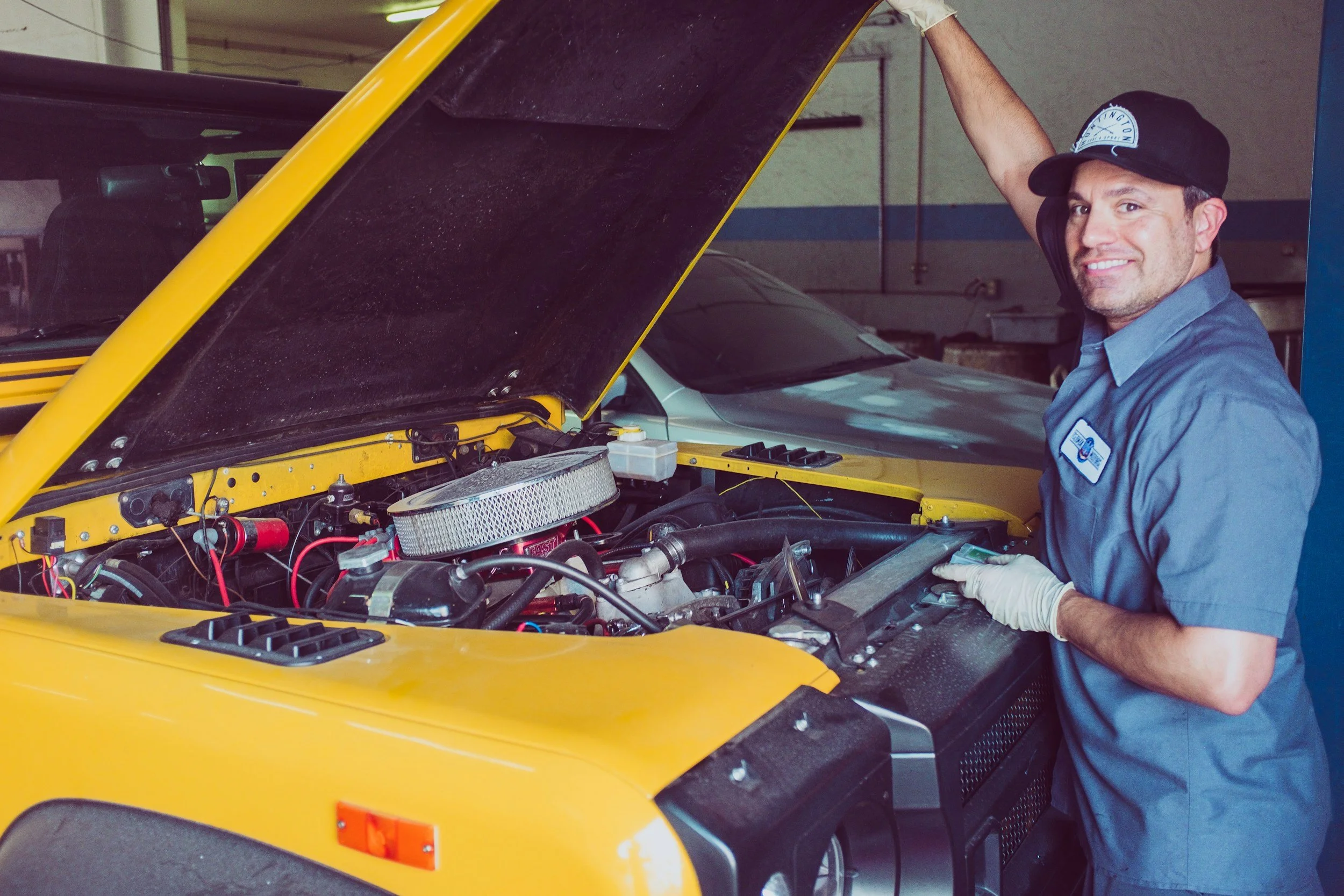 Mechanic working on engine of yellow car in garage
