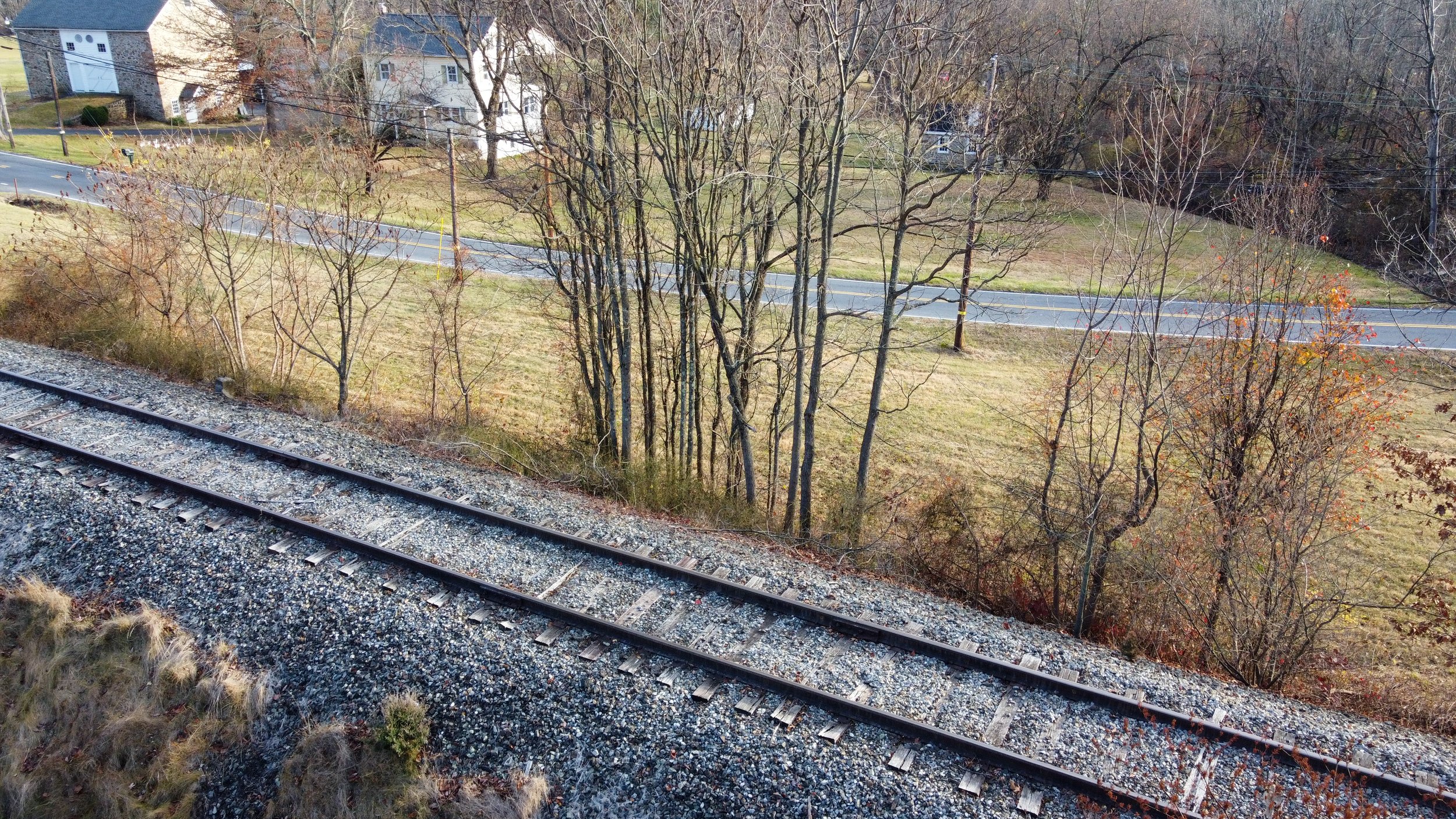 Railroad tracks with trees and a road in the background