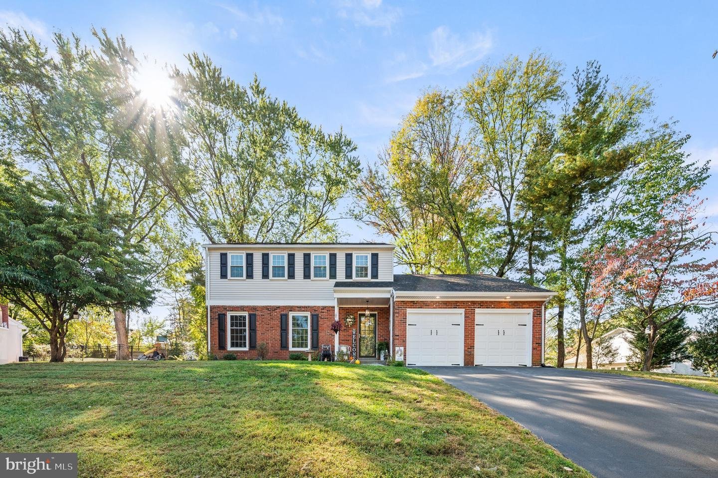 Two-story suburban house with brick and siding exterior, a double garage, surrounded by trees and a driveway.