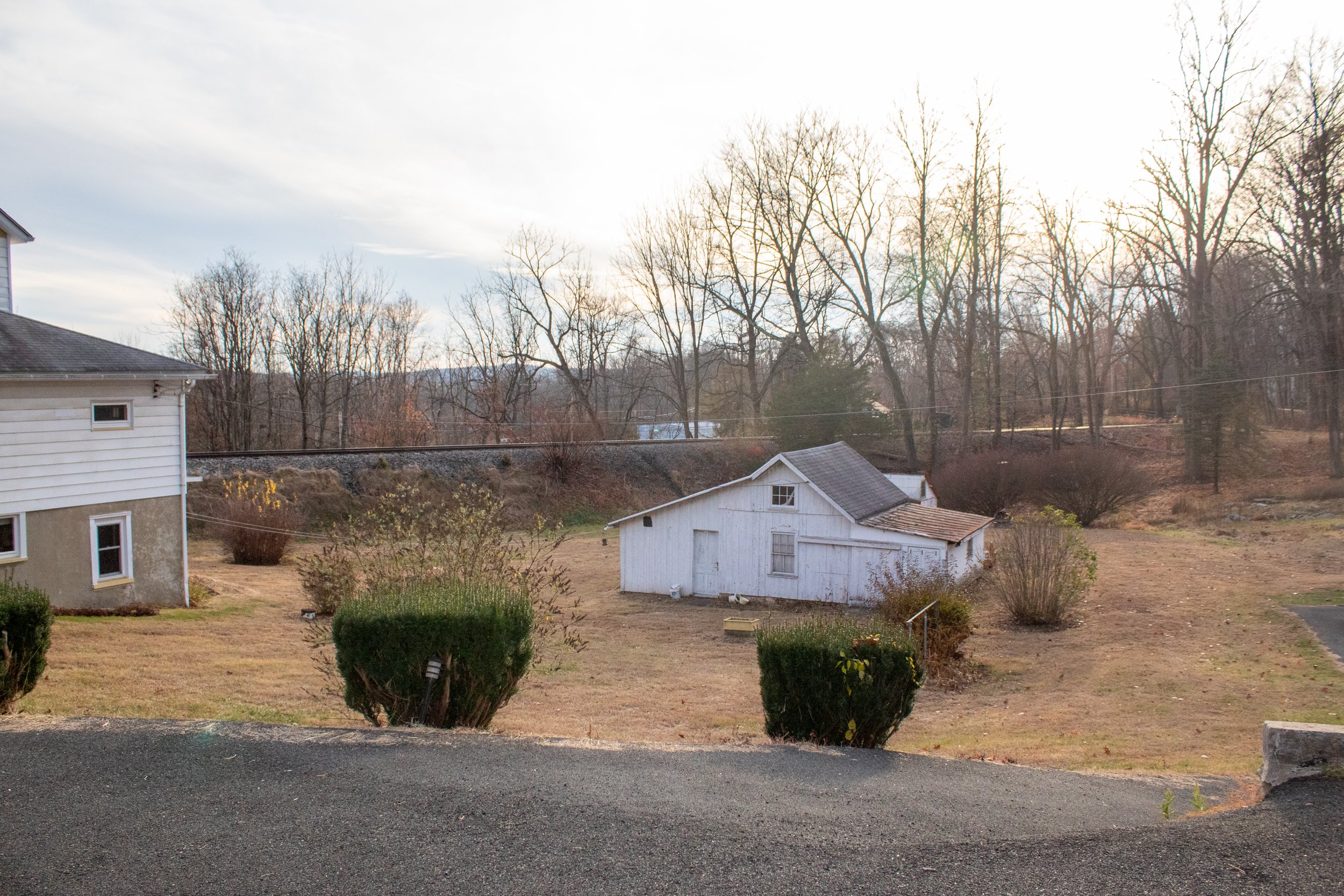White barn in a rural backyard with trees and a clear sky