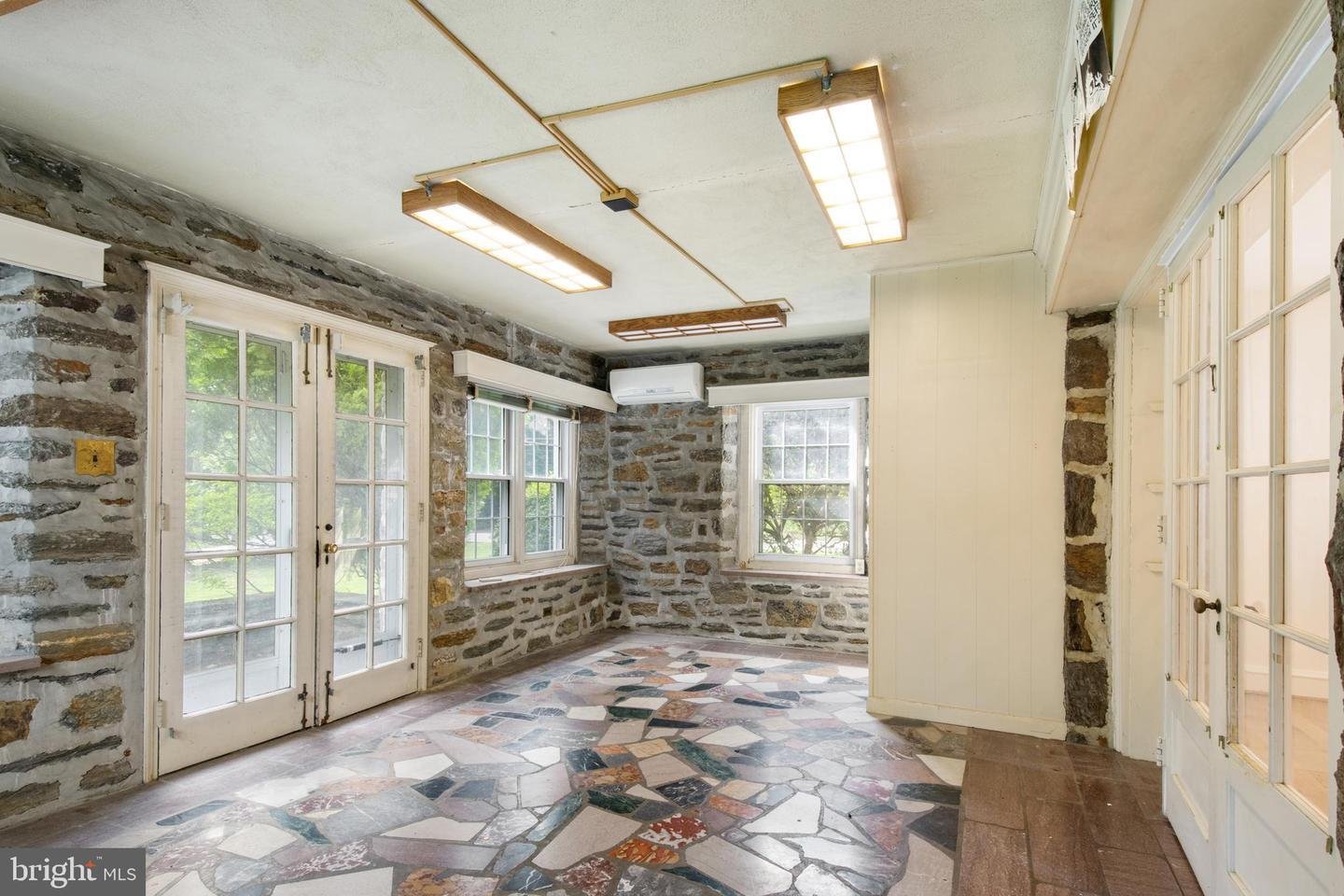 Sunroom with stone walls, mosaic floor, large windows, and French doors