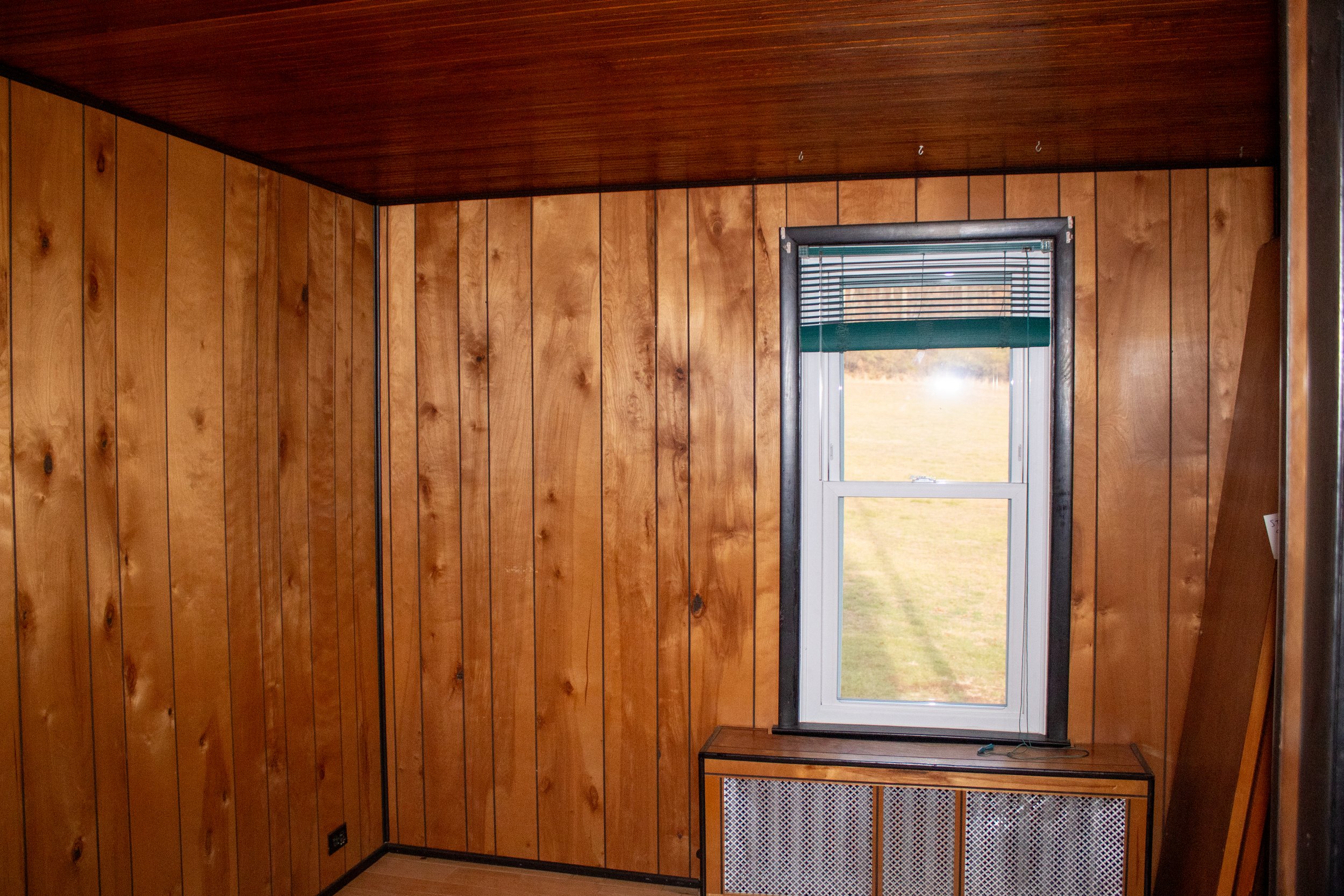 Room with wood-paneled walls and window with blinds