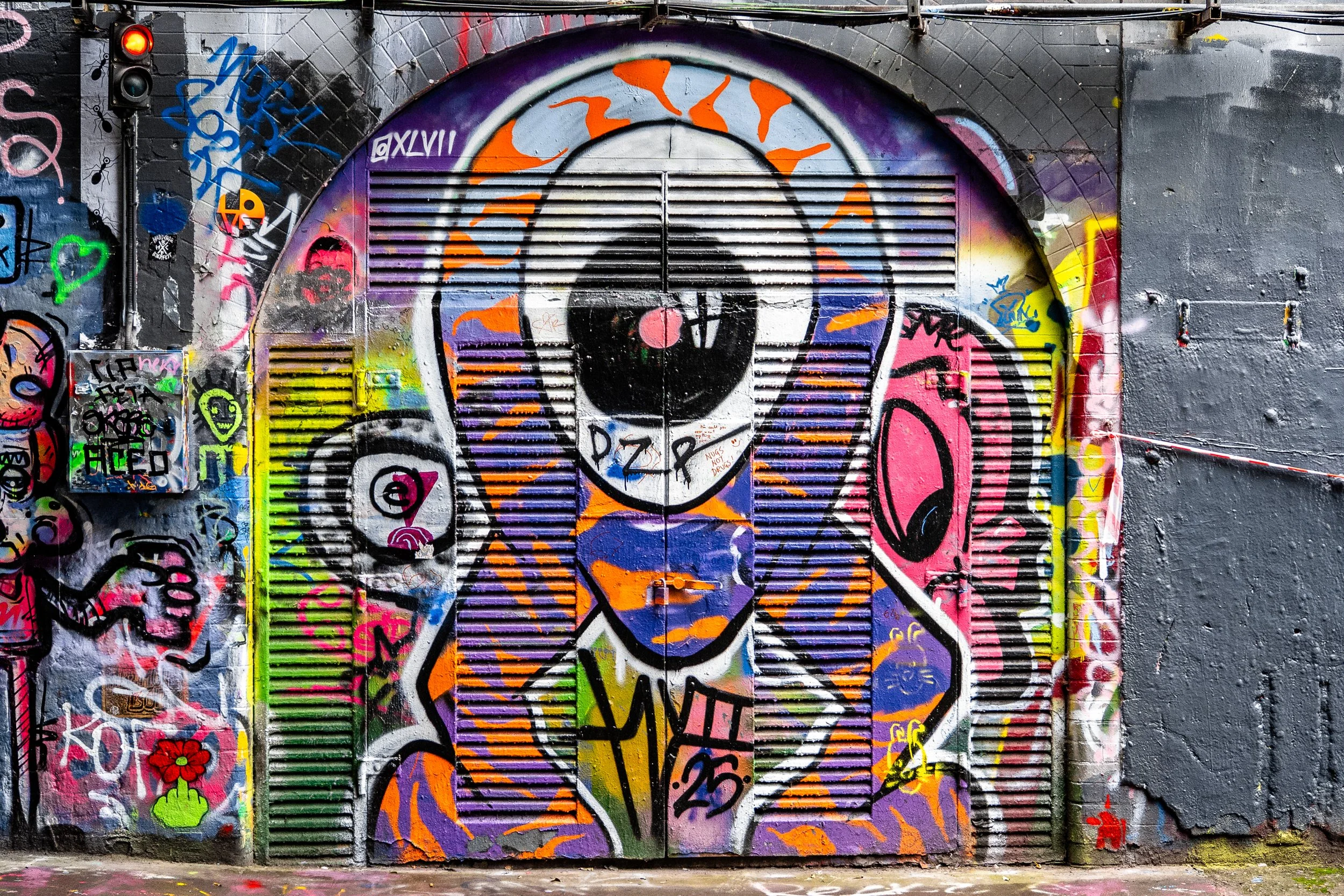 Graffiti street art of a stylized woman with purple hair, large eye, and colorful patterns on the door and wall.