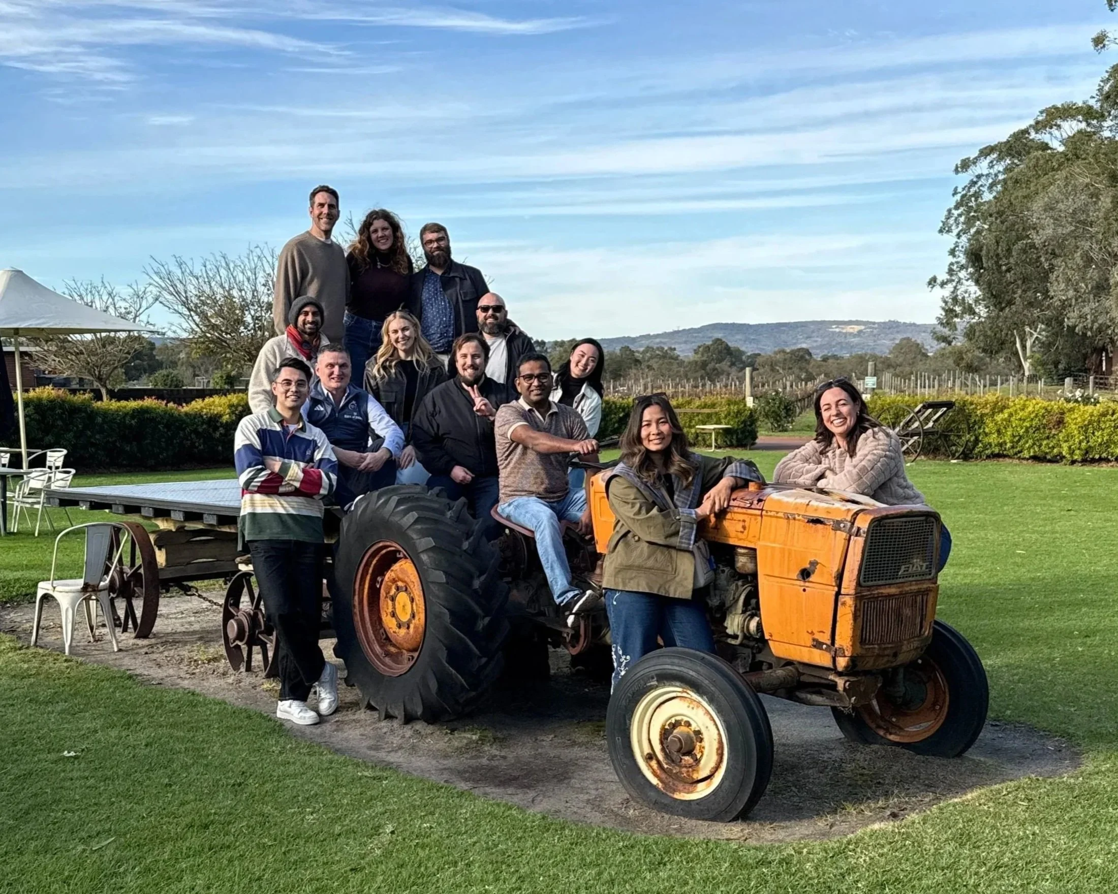 The Onbord team gathered outdoors on a vintage tractor at a countryside team day near Perth