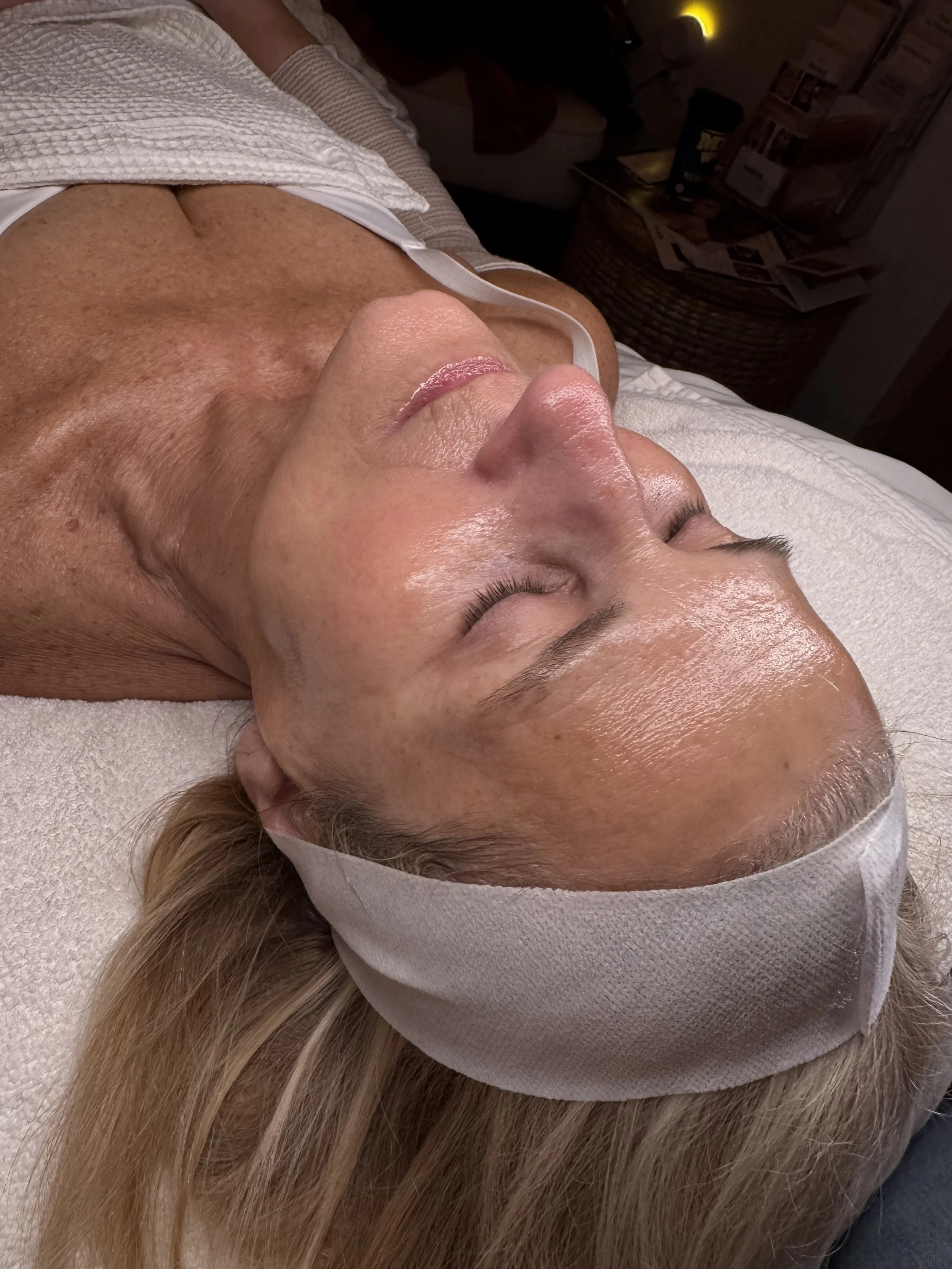 Person lying down with a white headband on a treatment bed in a spa setting.