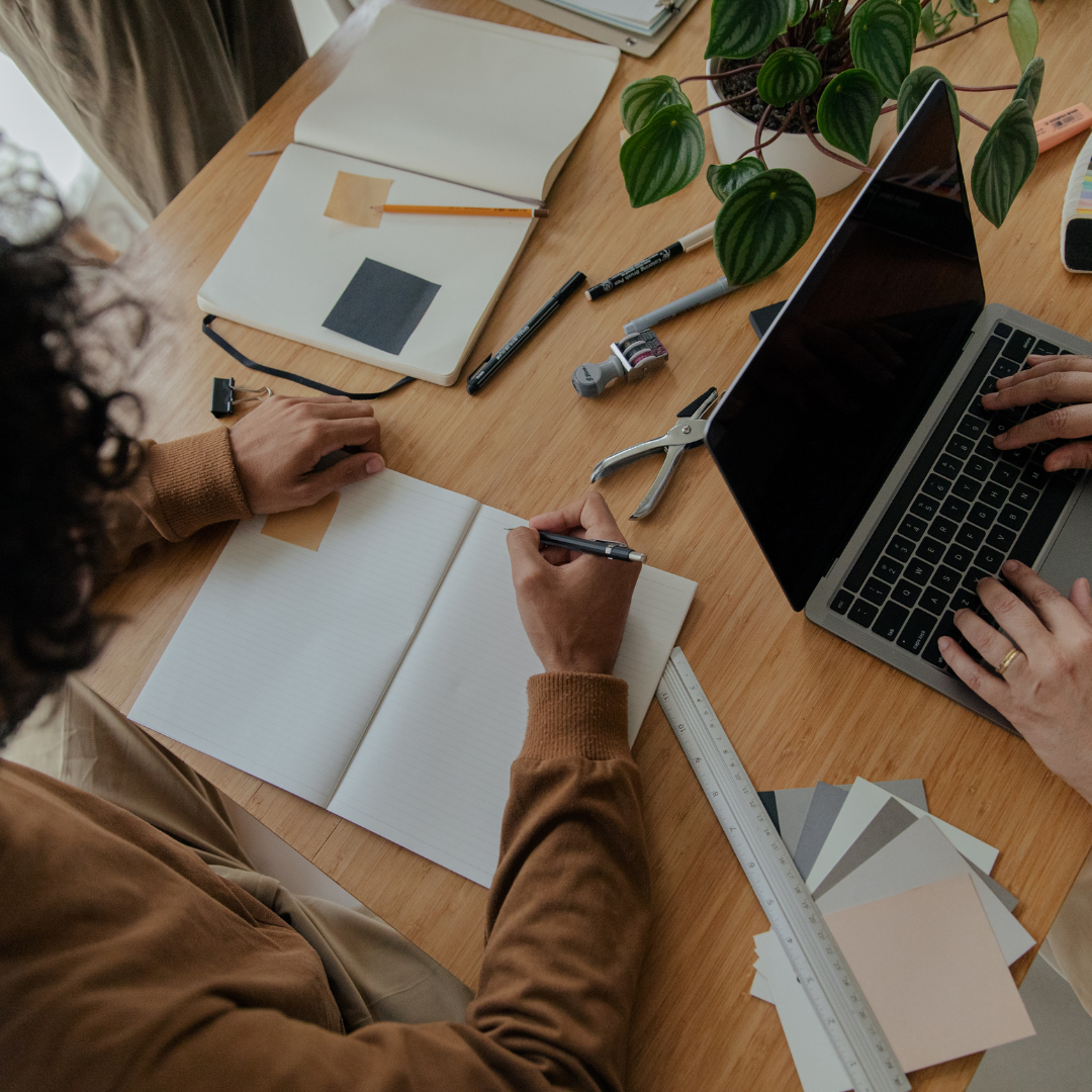 a group of people sitting around a table working on their laptops