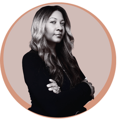 A young woman with long, wavy hair posing with her arms crossed against a beige circular background