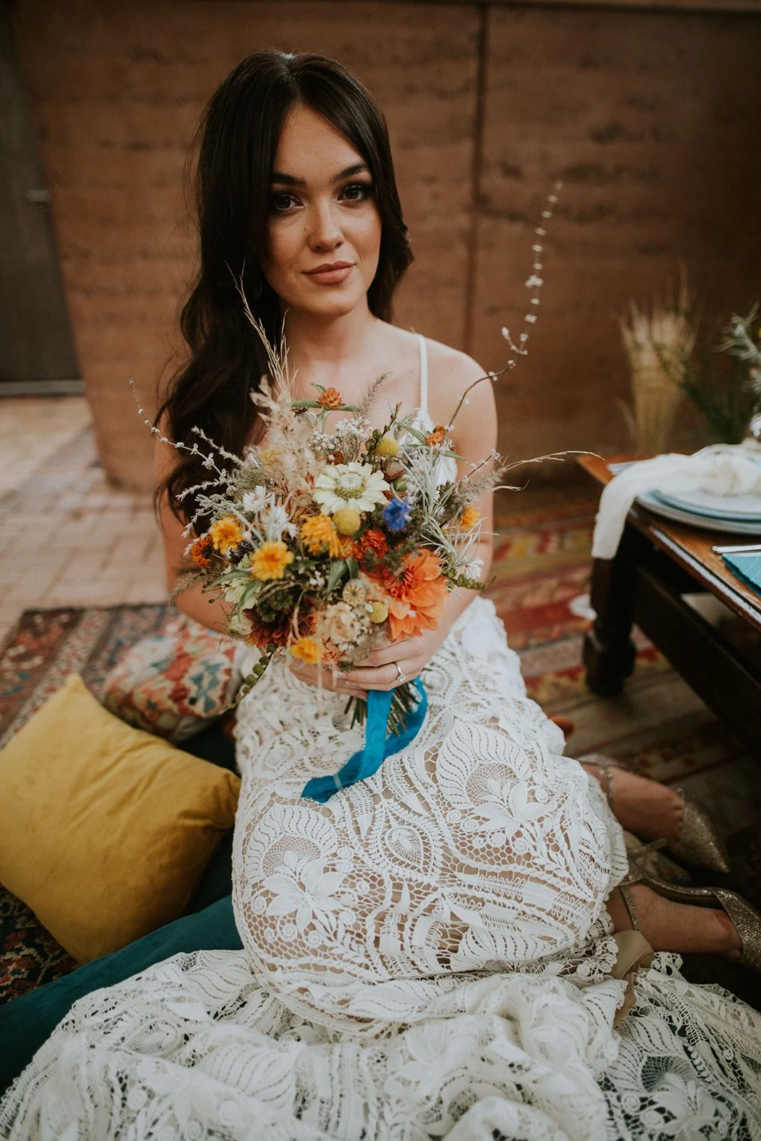 Woman in a white lace dress holding a colorful bouquet.
