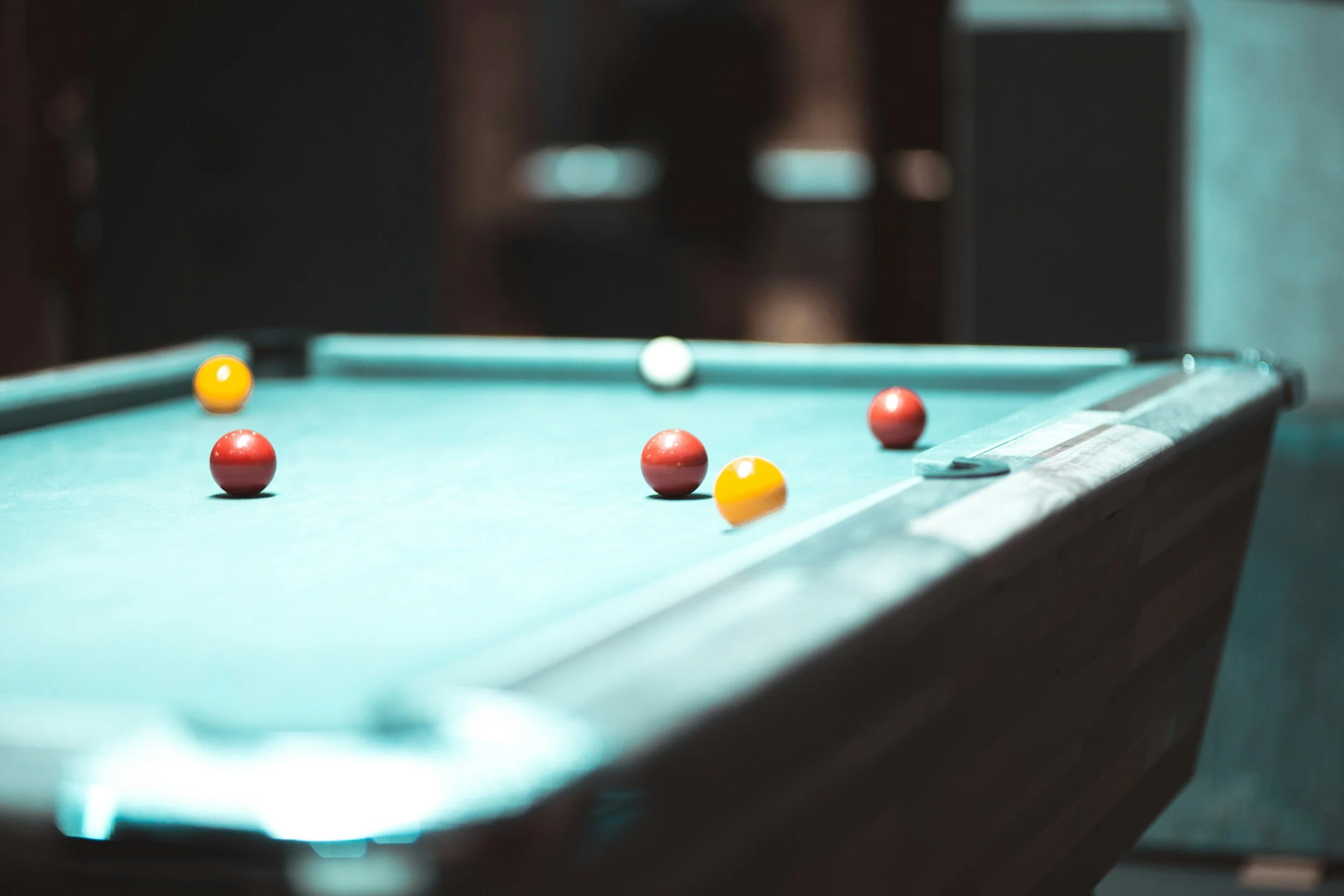 Billiards table with red, yellow, and white pool balls in a dimly lit room