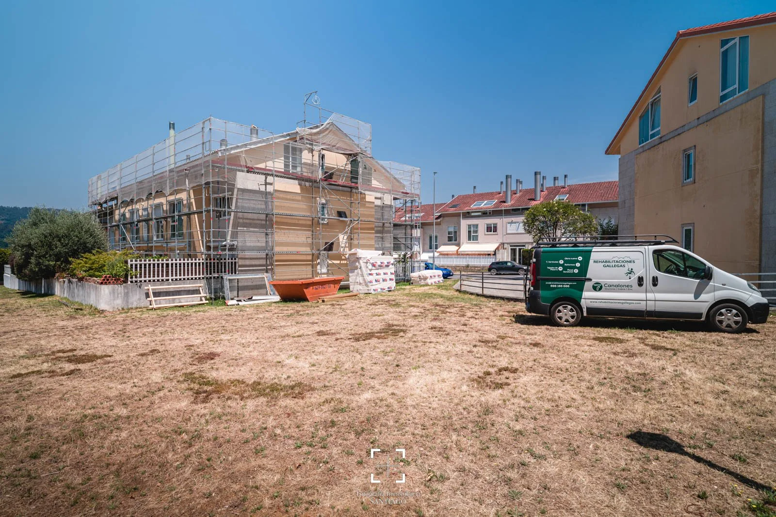 Construcción de una casa con andamios en un vecindario. Vehículo de reparaciones de Galicia en primer plano.  Fotografía profesional de obra para empresa constructora