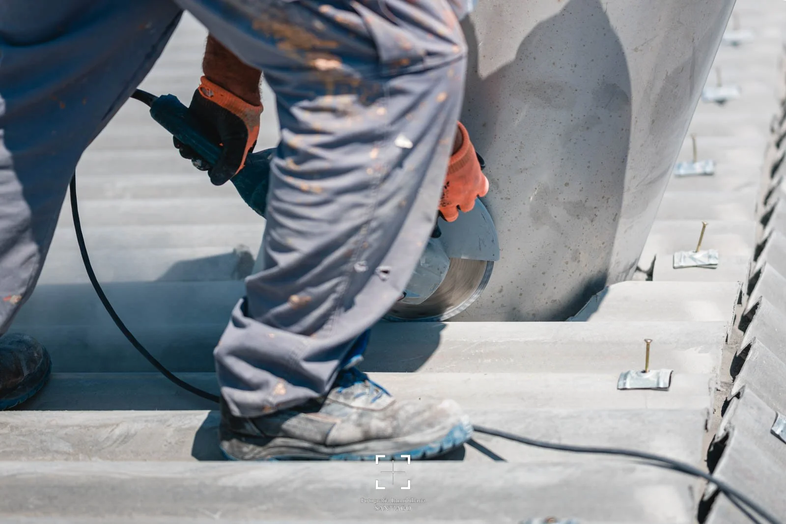 Trabajador usando gafas y guantes cortando concreto con una amoladora en un sitio de construcción. fotografia comercial y negocios