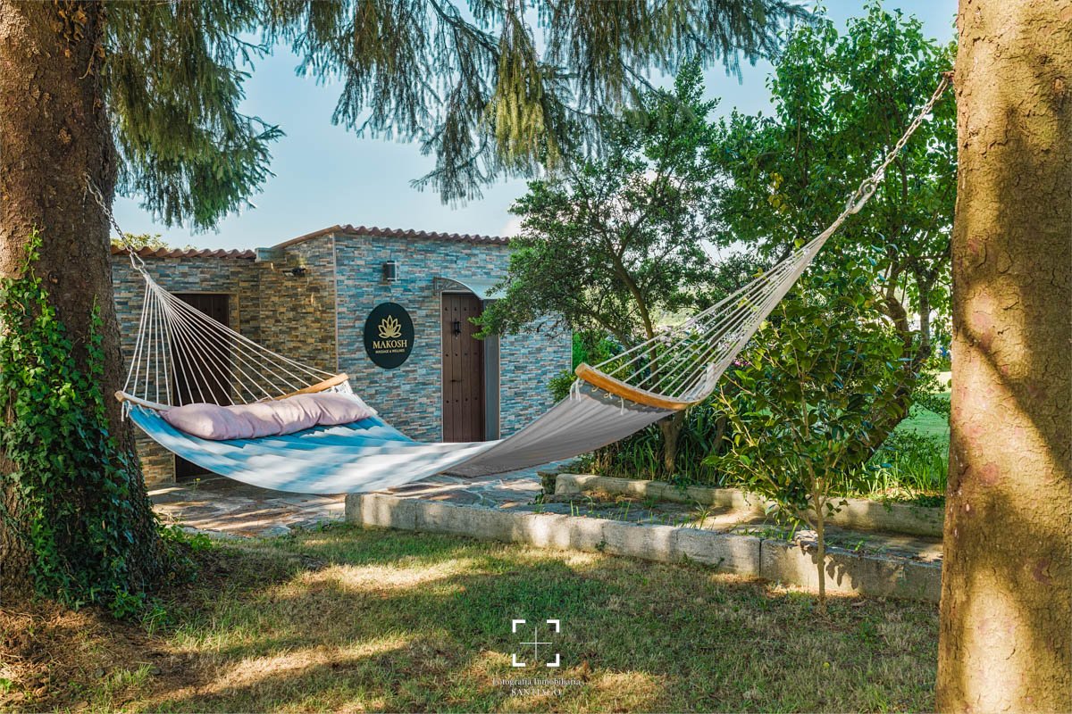 Columpios colgantes entre dos árboles en un jardín, con un fondo de edificio de piedra y vegetación