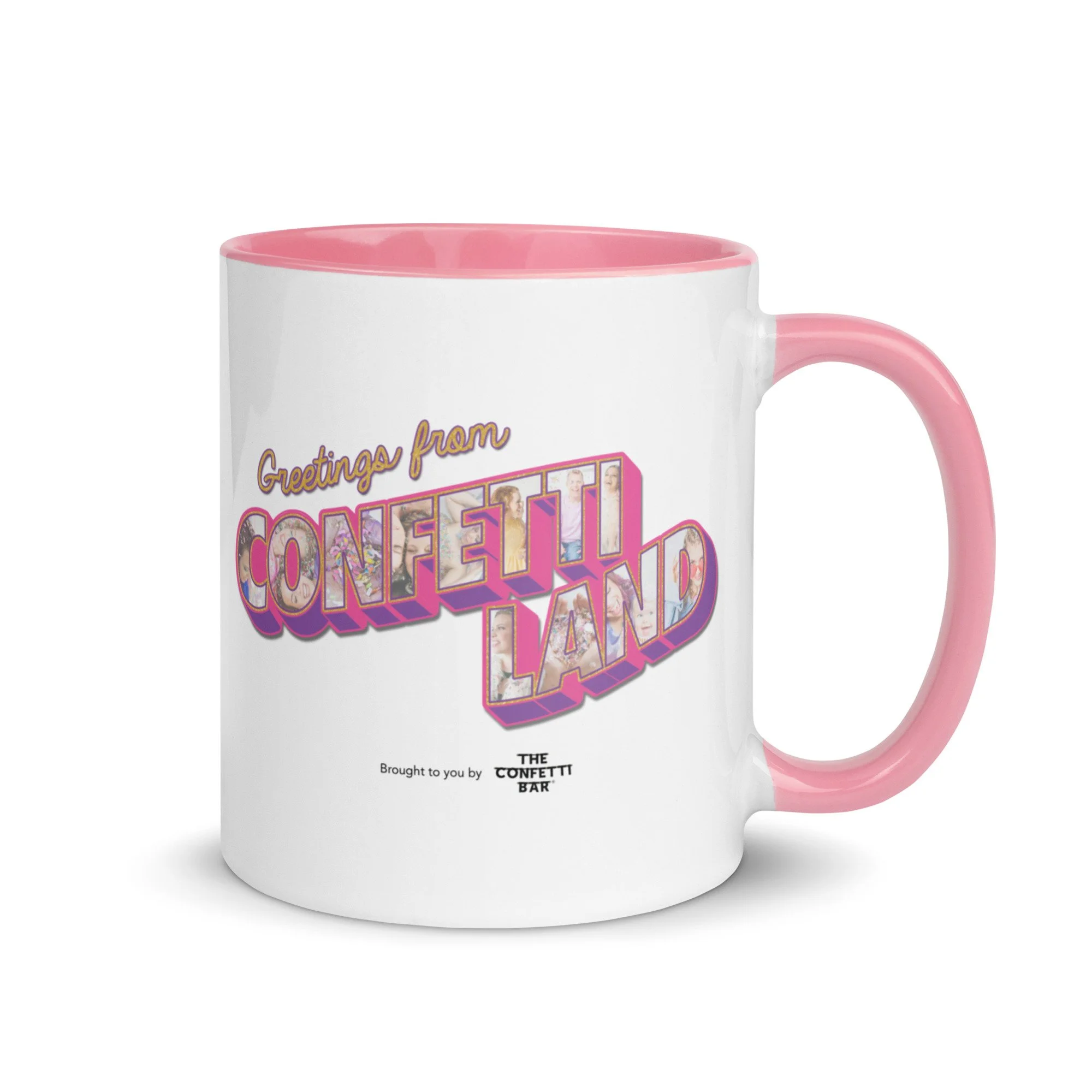 White ceramic mug with pink interior and handle featuring a vintage-style design that reads 'Greetings from Confetti Land' with colorful, decorative text and small images within the letters, and a smaller text below that says 'Brought to you by THE CONFETTI BAR'.