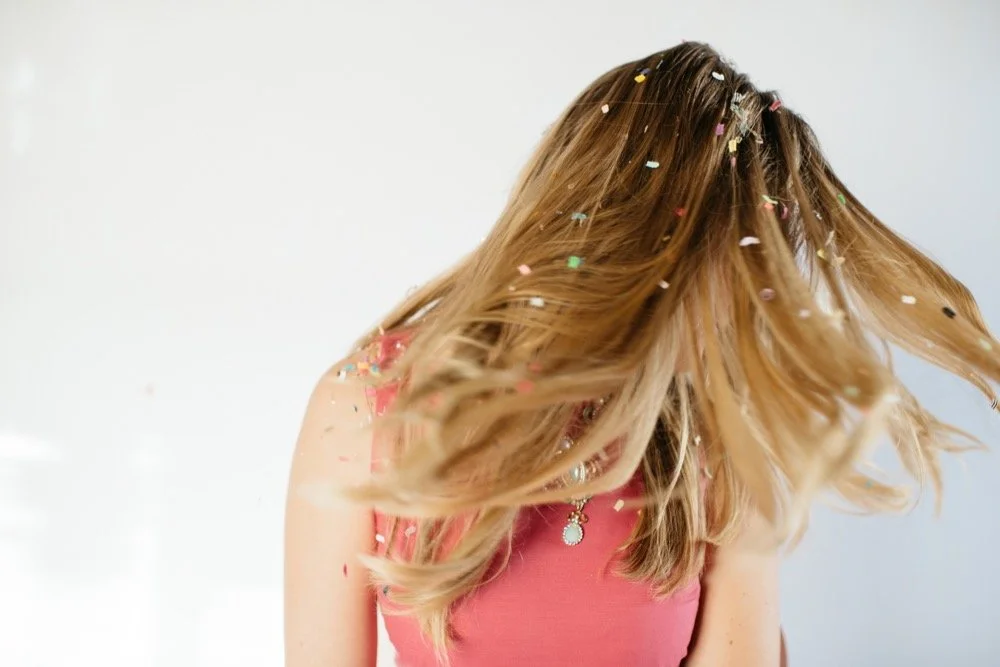 blonde haired girl flipping her hair around and it's full of confetti