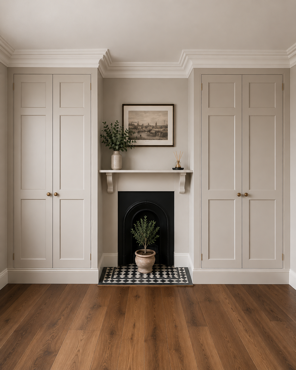 Living room with beige built-in cabinets on either side of a fireplace, decorated with a sliding shelf. The shelf holds a potted green leafy plant and a small decorative item with sticks. A framed picture of a cityscape hangs above the shelf. The fireplace has a black arch and a potted small green plant in front of it. The floor is wood, and the room has crown molding.