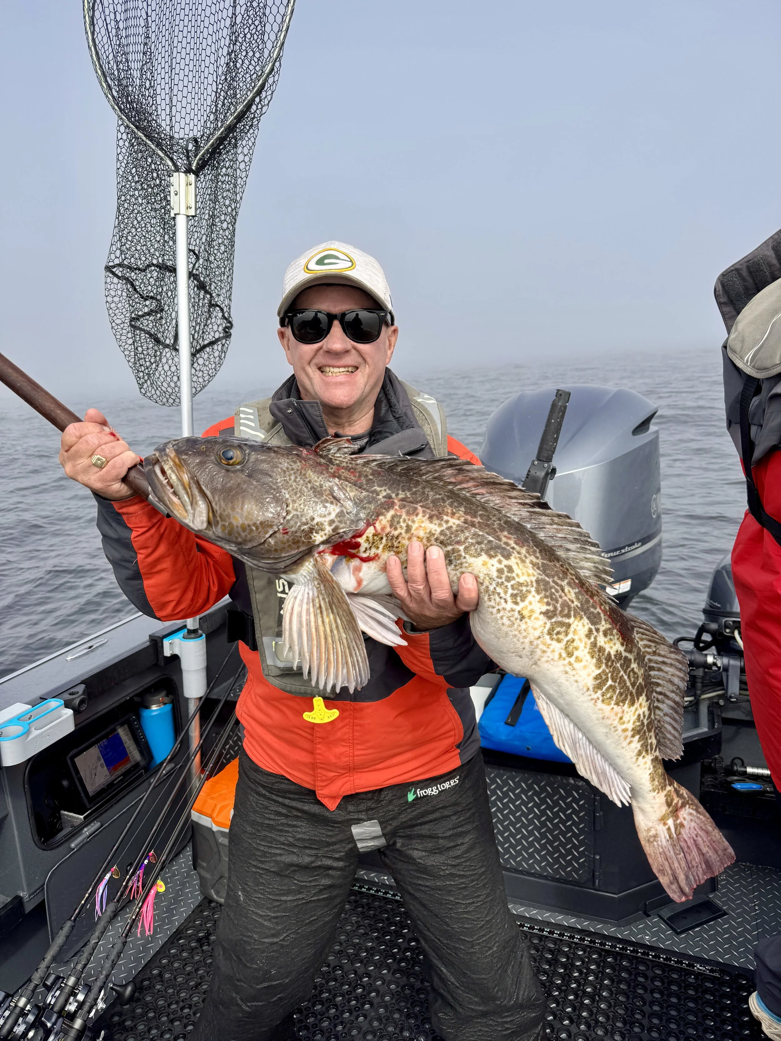 Man on the ocean out of Depoe Bay holding a large lingcod caught on a herring.