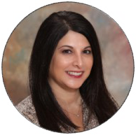 Jennifer Anderson, principal at Holy Trinity School in San Pedro, CA with long dark hair smiling against a blurred, colorful background.