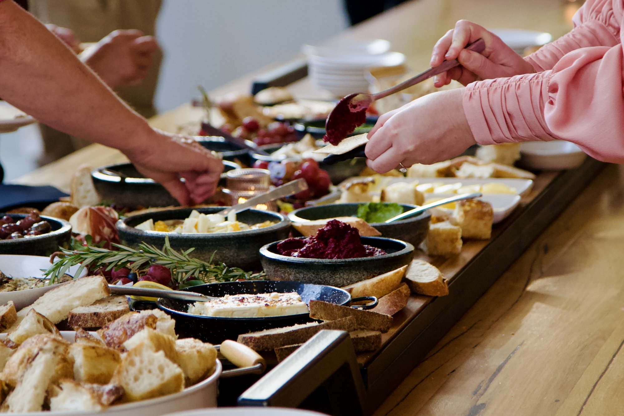Guests serving from gourmet buffet table at Paddock Bakery Geelong event with artisanal dishes.