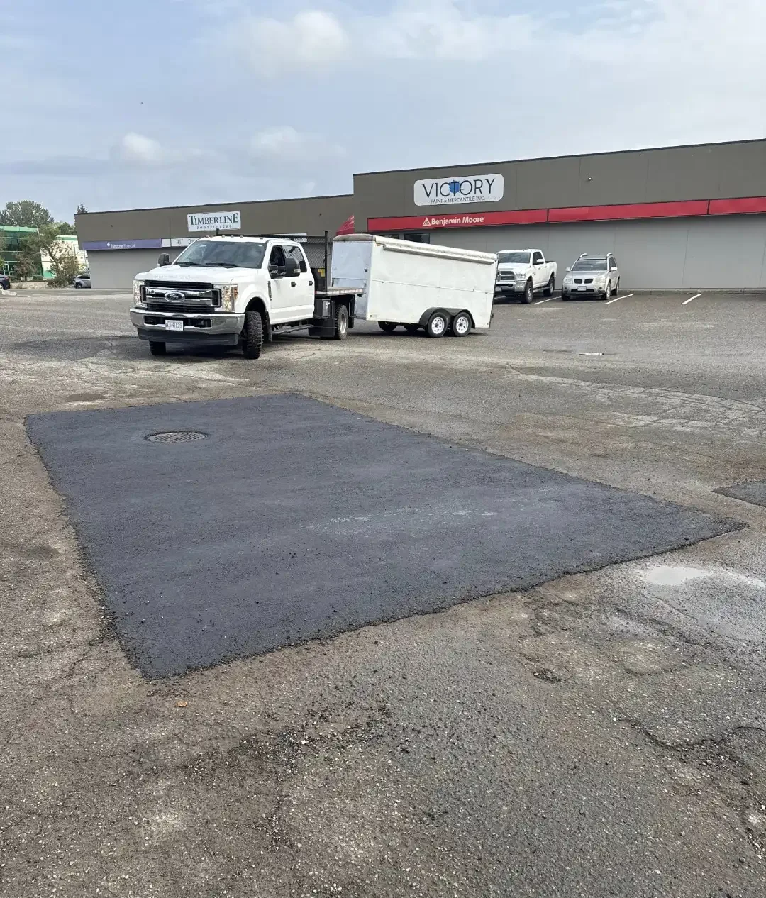 Freshly patched pothole in a commercial parking lot, demonstrating professional asphalt repair services