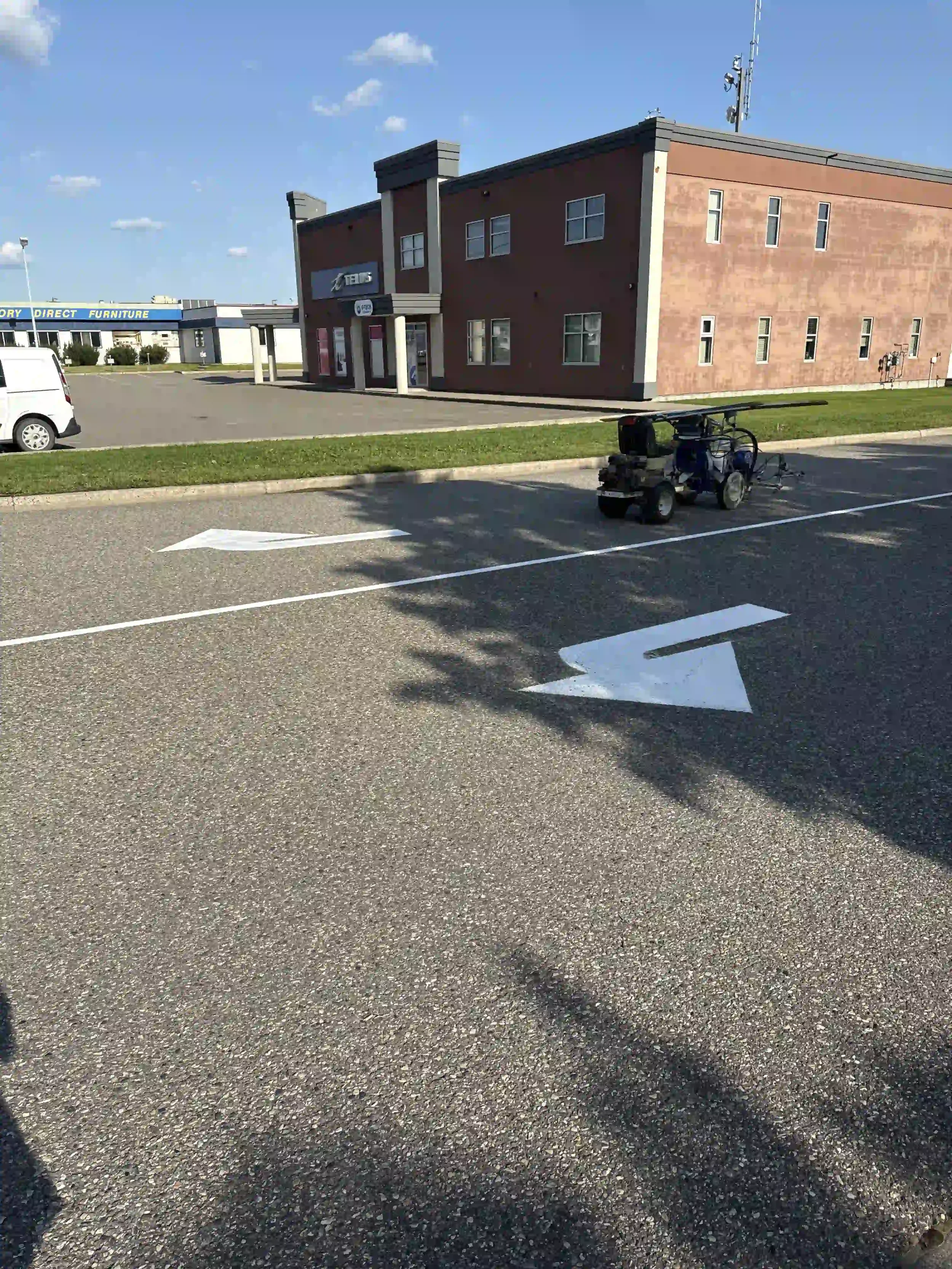An Epic Pavement line painting machine applying fresh white directional arrows in a commercial parking lot.