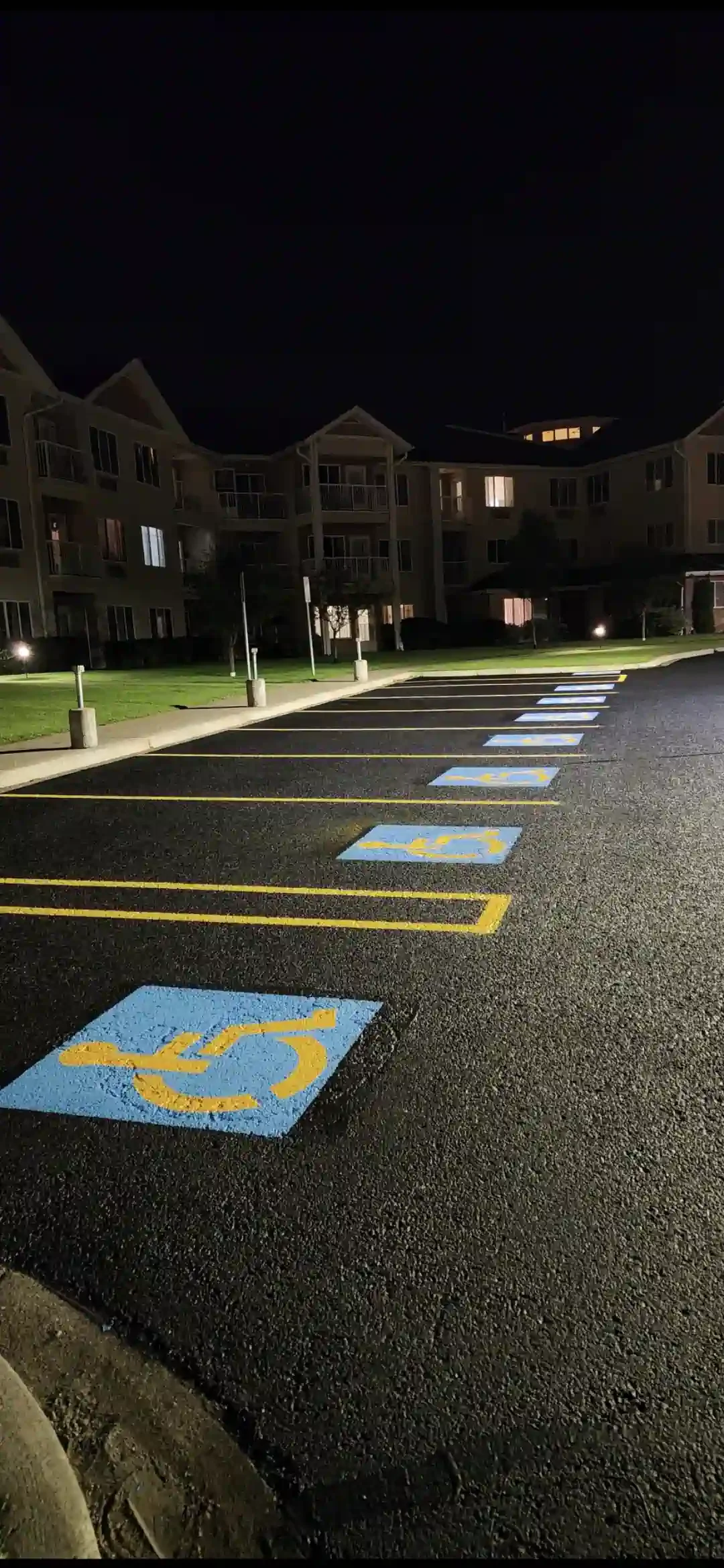 Empty parking lot at night with wheel chair accessible parking spaces marked in blue and yellow.