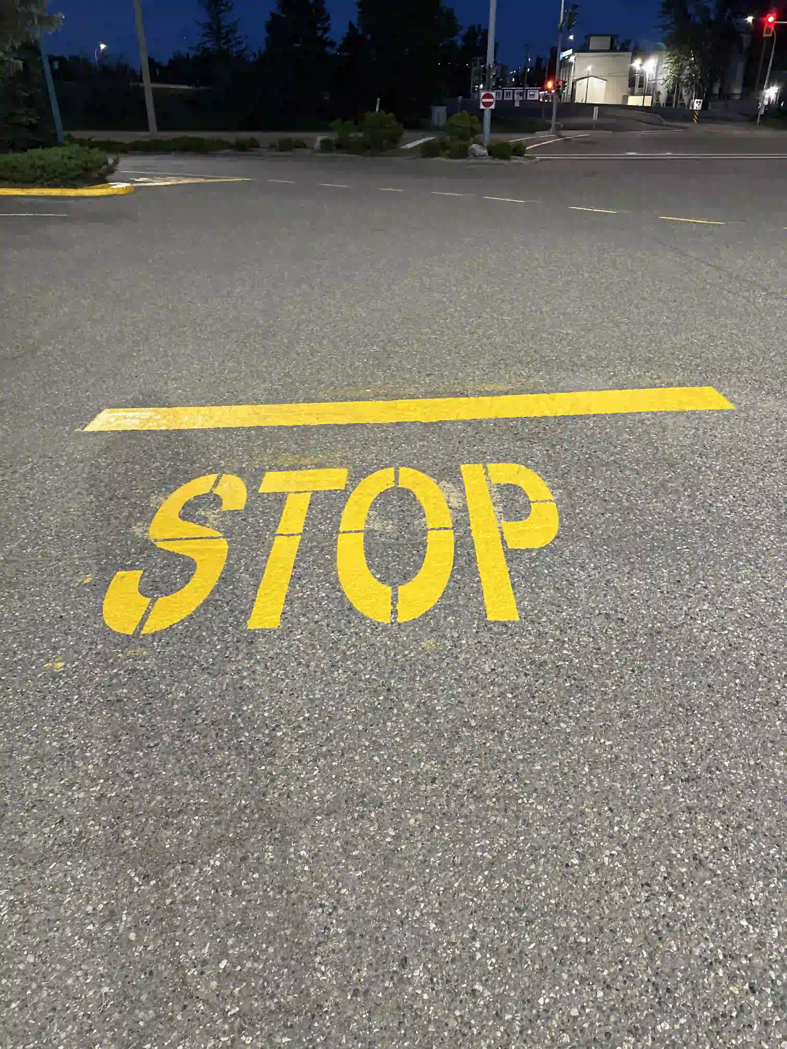 Freshly painted yellow stop line and pavement stencil in a commercial parking lot by Epic Pavement.