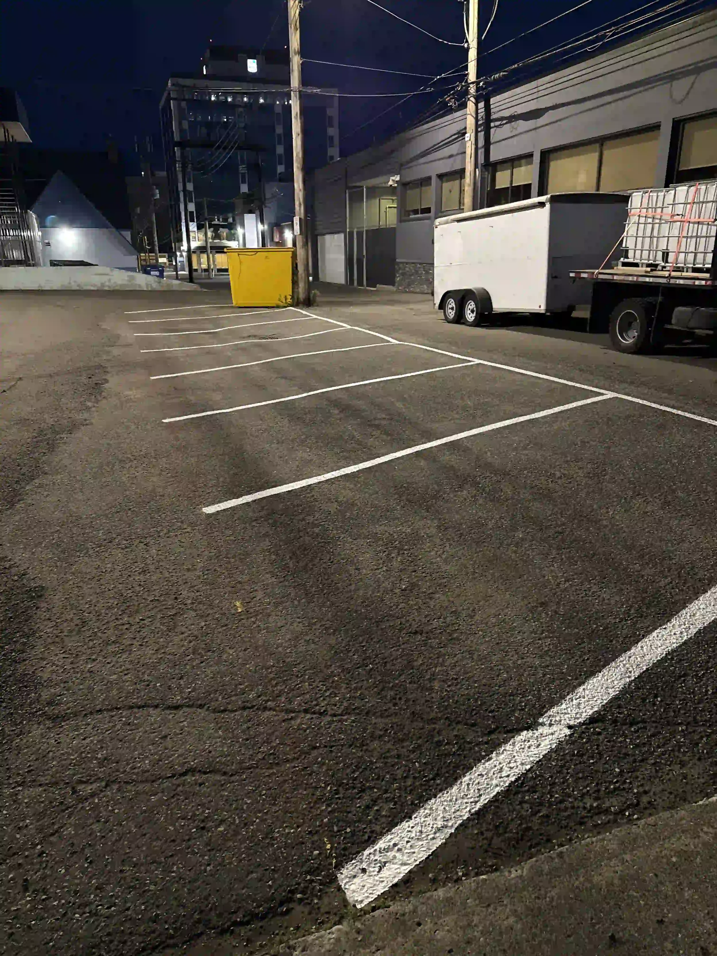 Freshly painted white parking stall lines in a commercial back lot following professional line painting services by Epic Pavement.
