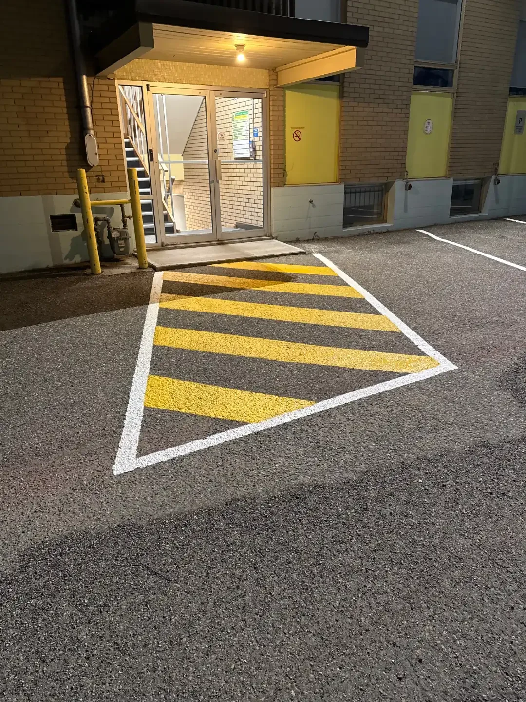 Parking lot line painting with yellow safety hatch markings at commercial entrance - Epic Pavement