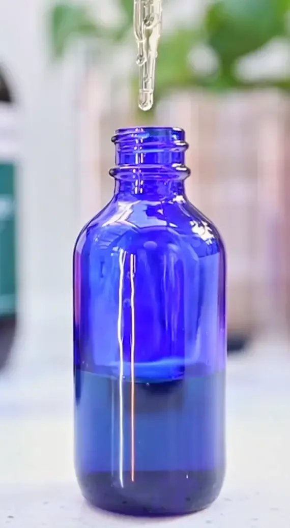 Herbal tincture dropper, dropping herbal medicine into a blue bottle