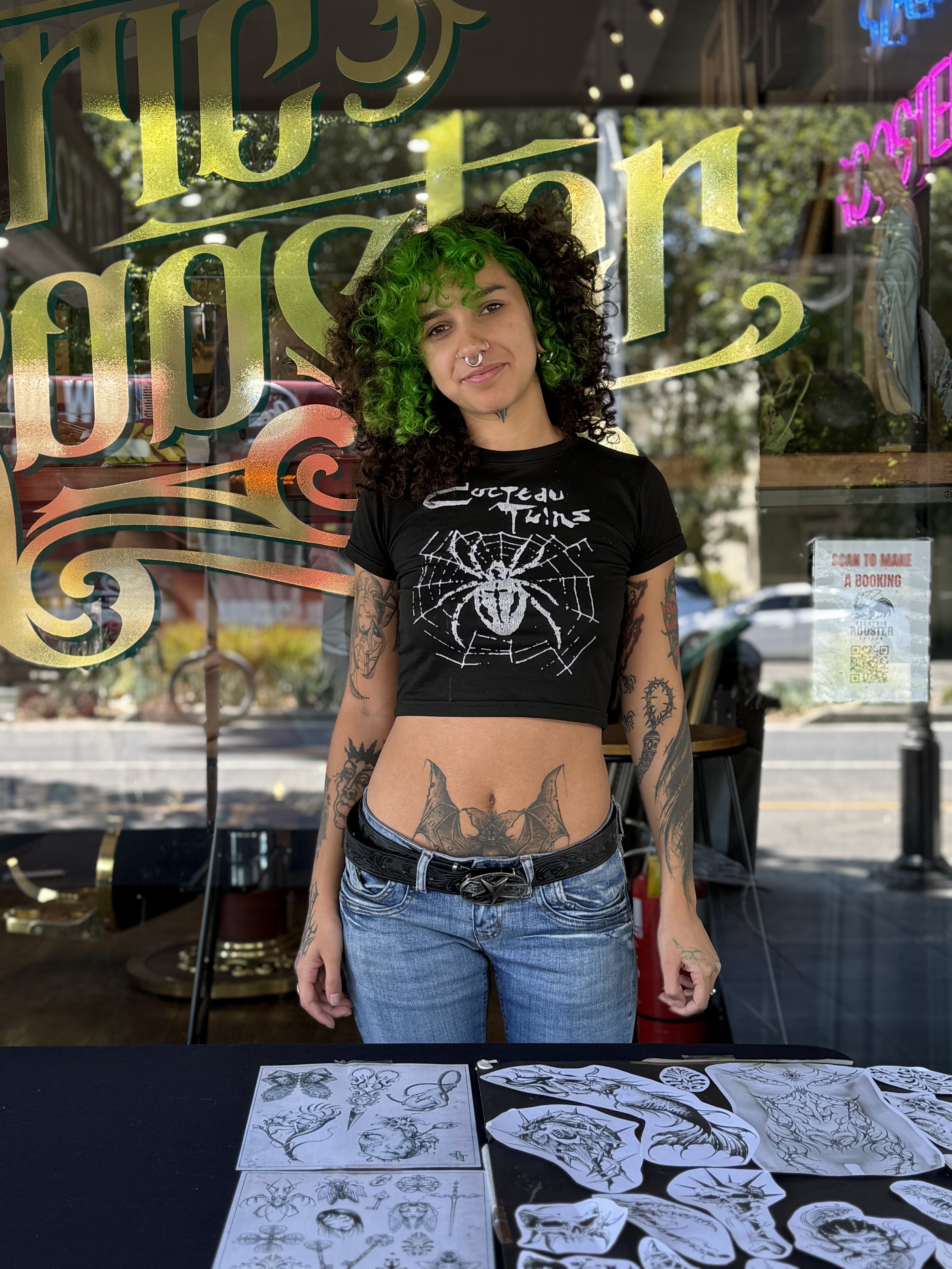 A young man with a headlamp and black glove tattooing an arm in a tattoo studio.