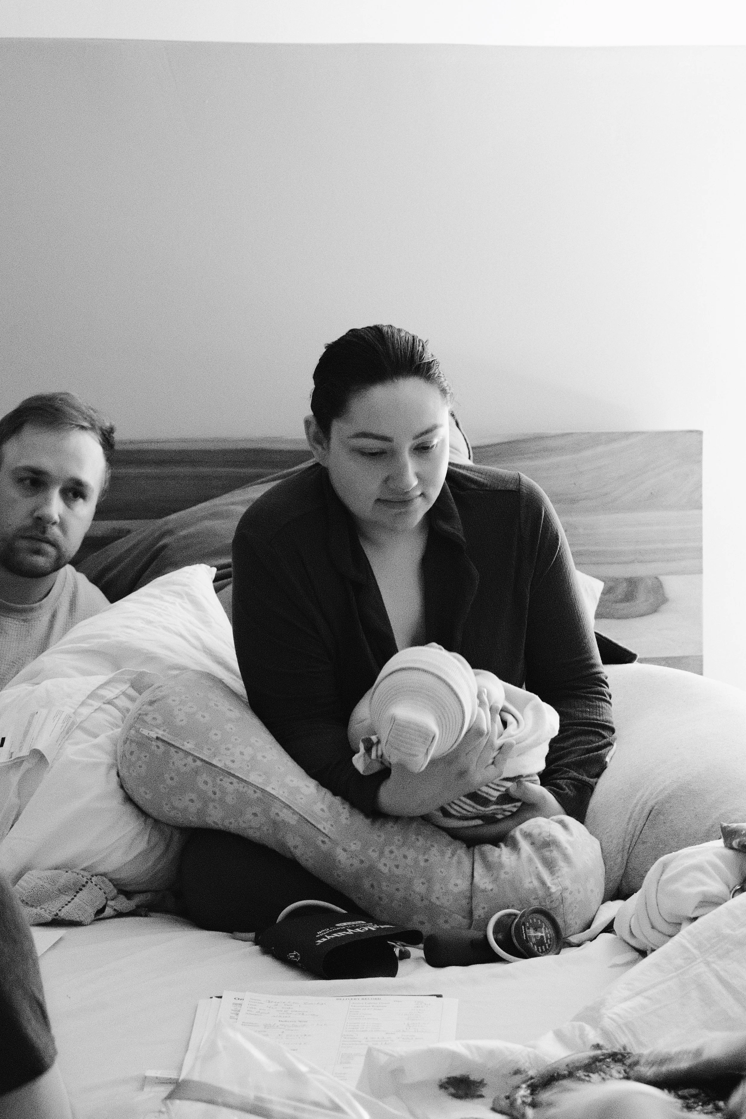 Close up documentary style photograph of a mother holding her baby skin to skin after home birth with local doula support.