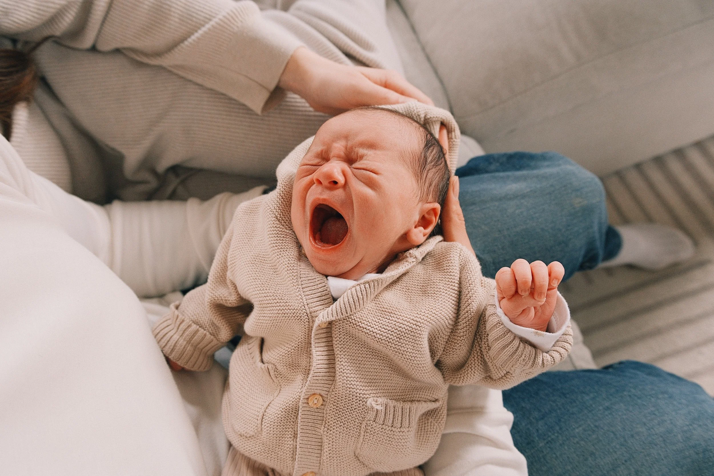 Overnight postpartum night doula cradling a yawning newborn baby during night care in a Roncesvalles Toronto home