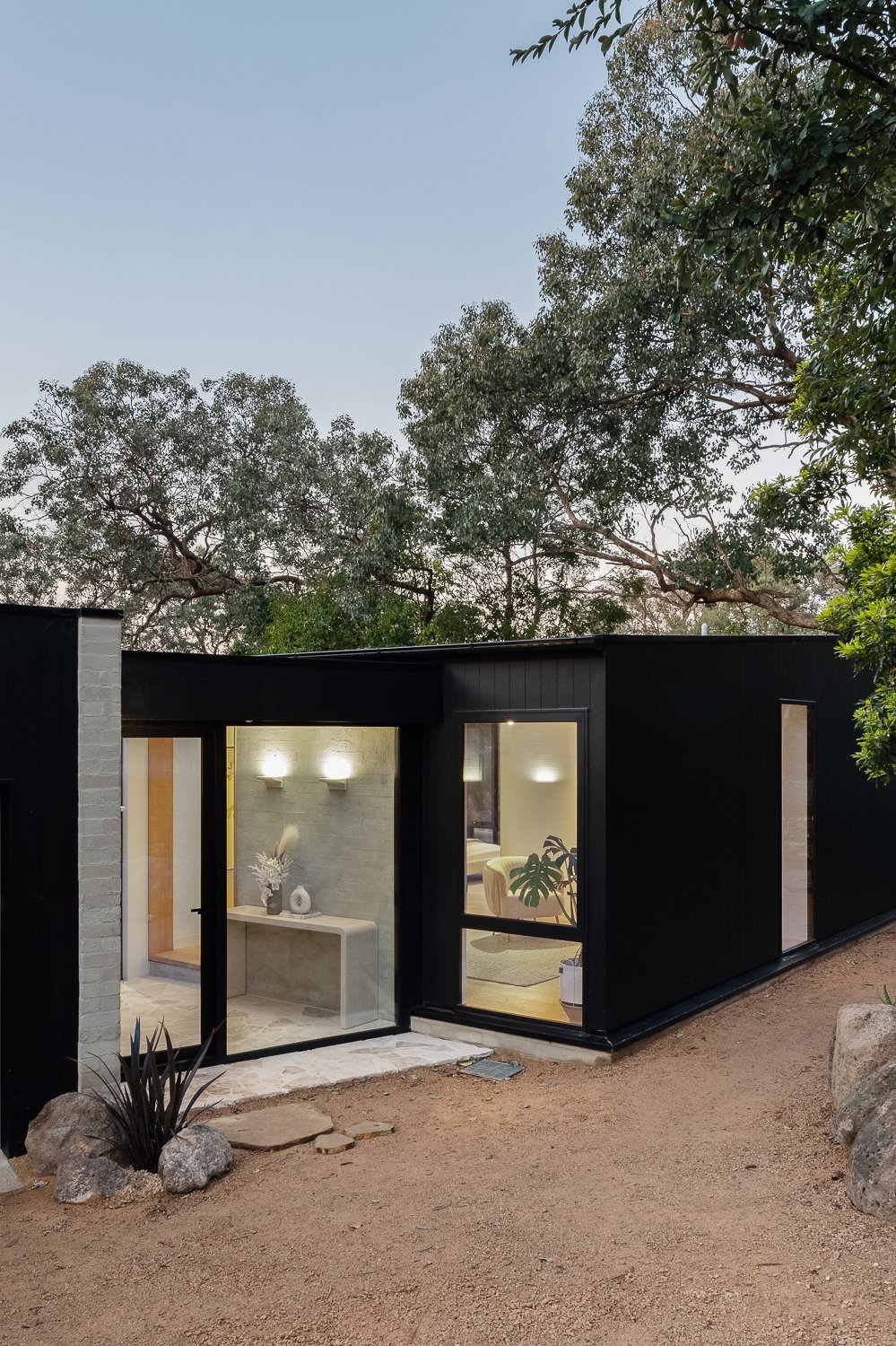 Japandi House entry at dusk, black cladding and warm lighting, by FTLO Design