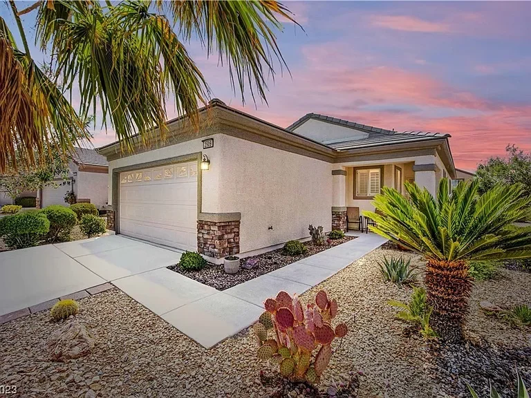 Exterior view of the single-story home at 2509 Jade Sky Street in Henderson, Nevada, featuring a two-car garage, desert landscaping, palm trees, and a colorful sunset sky.