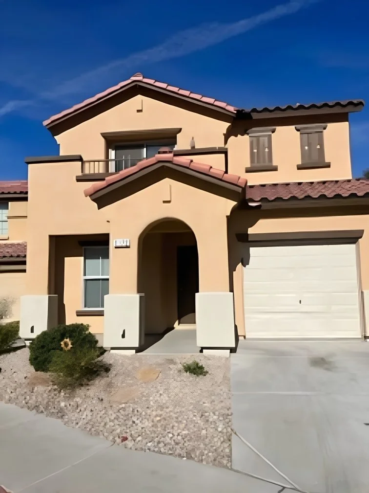 Exterior view of the two-story home at 1172 Paradise Desert Avenue in Henderson, Nevada, featuring a stucco façade, red tile roof, private balcony, attached garage, and desert landscaping.