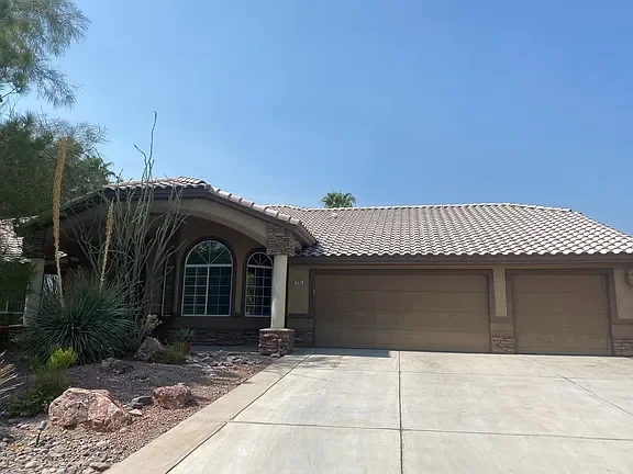 Front exterior of a spacious 4-bedroom single-story home at 9395 W Verde Way in Las Vegas, NV, featuring a three-car garage, desert landscaping, and a large driveway on a half-acre cul-de-sac lot.