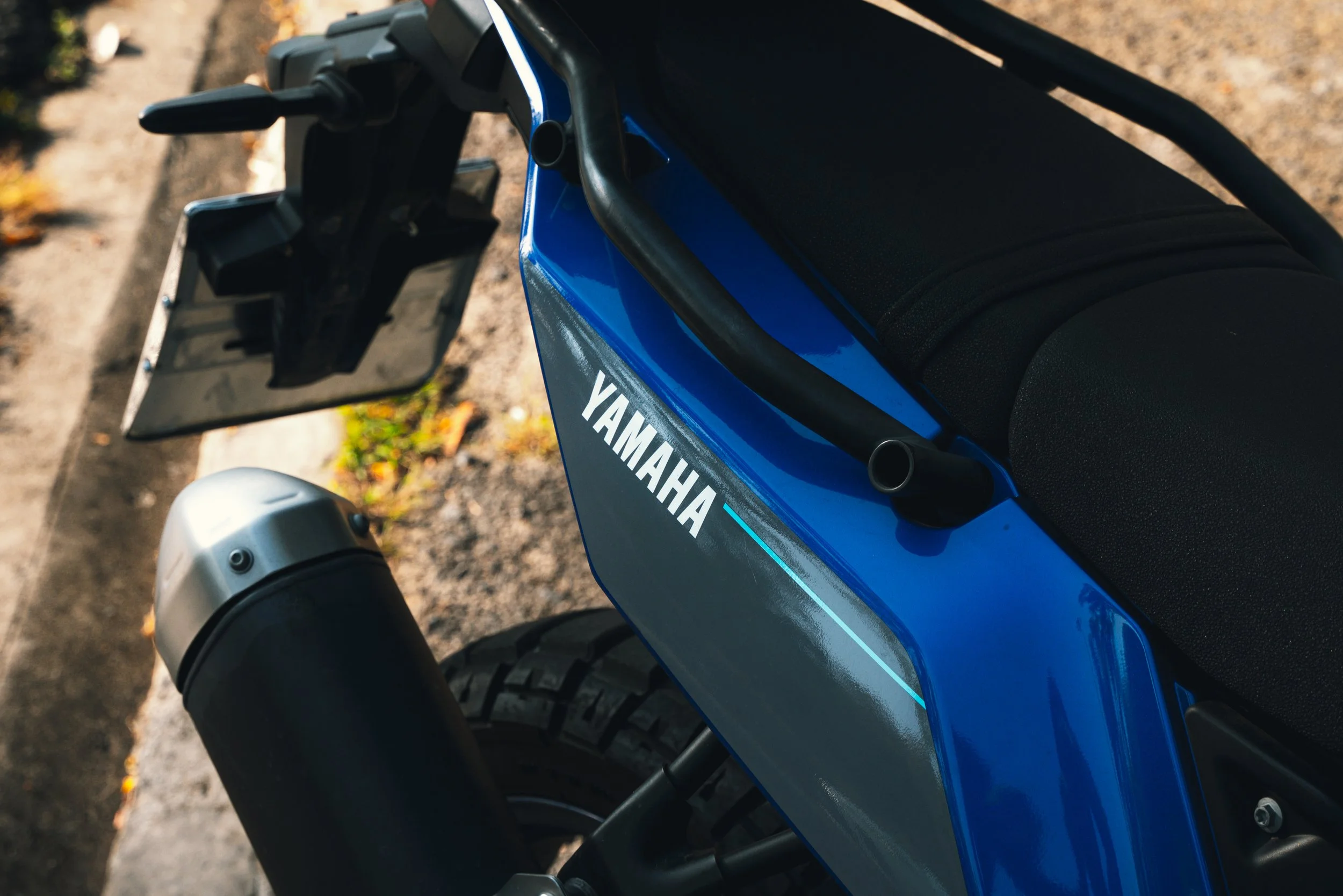 Close-up of a blue Yamaha motorcycle with black seat and rearview mirror, showing the Yamaha logo on the side panel.