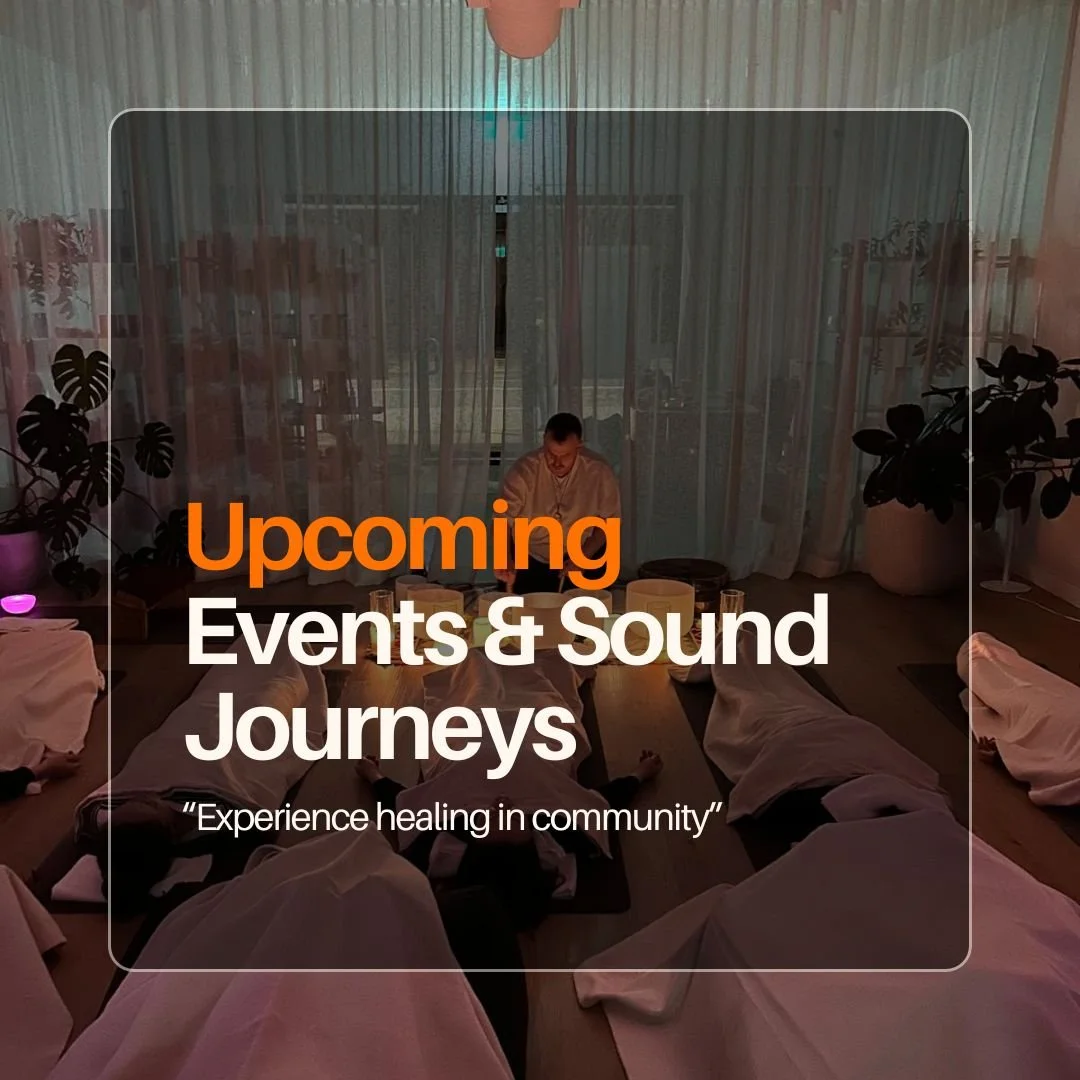 A person leading a sound bath session in a dimly lit room with others lying on mats covered with white towels.