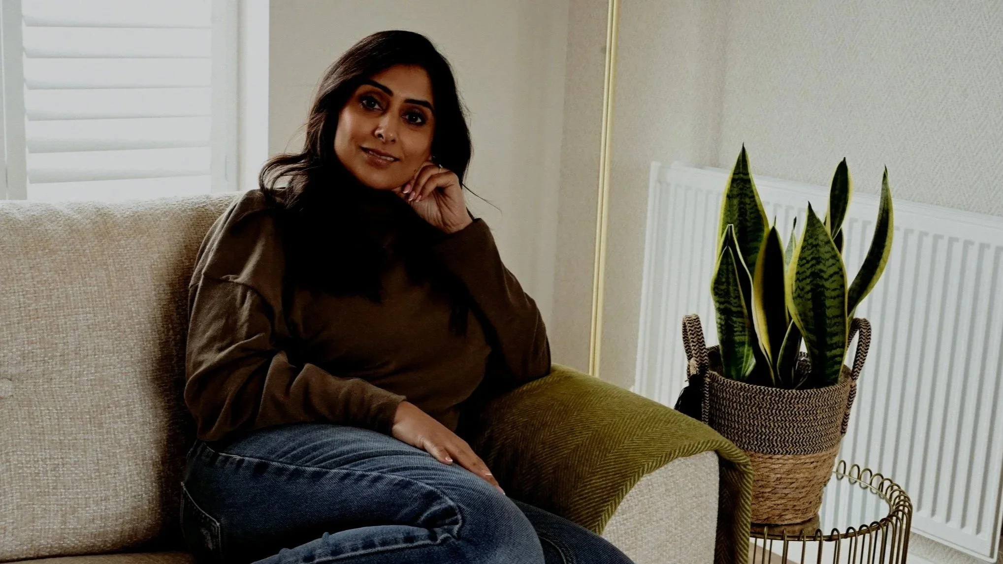 Lady sat on a sofa with her legs curled up beside her