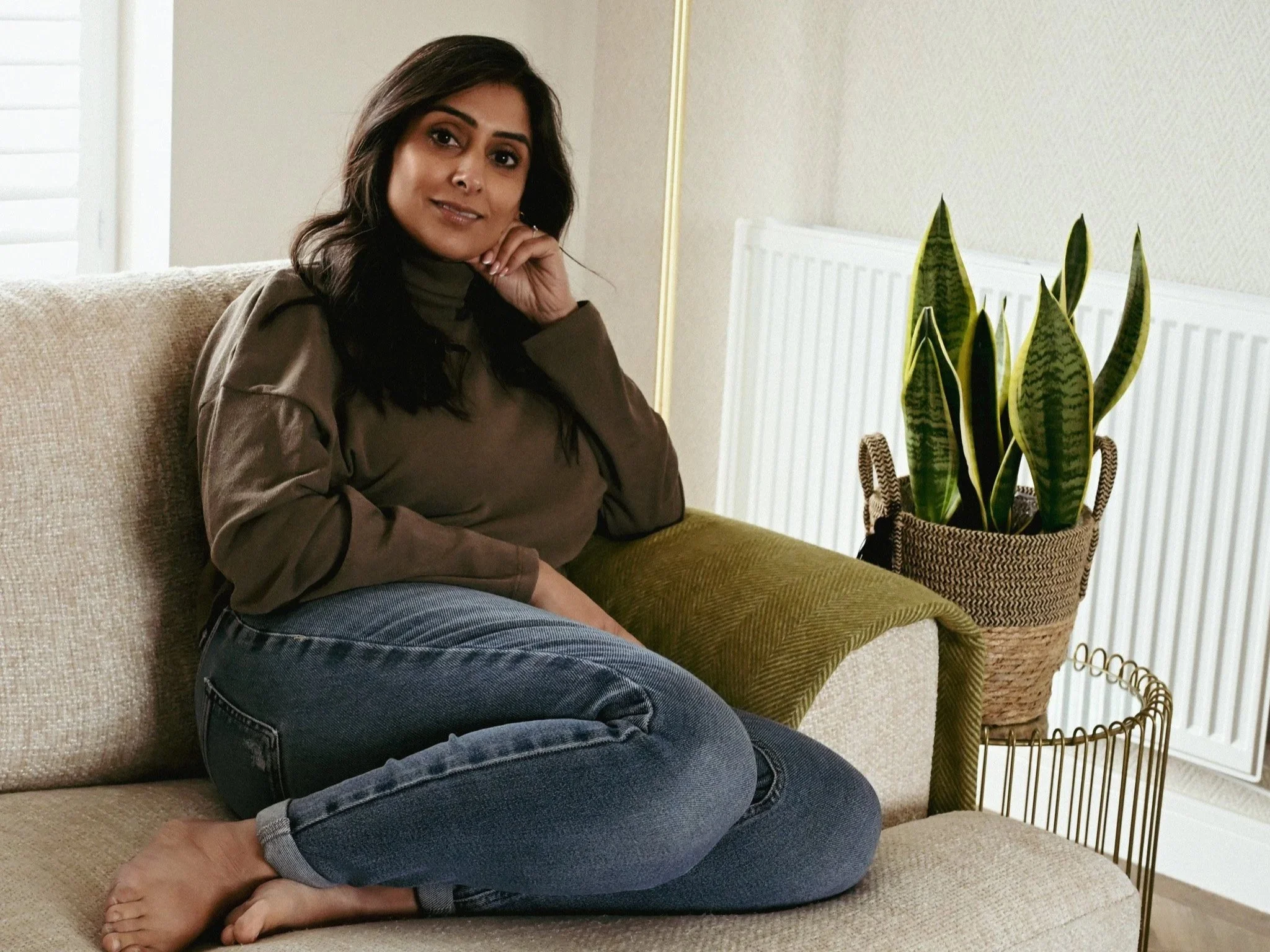 Lady sat on a sofa with her legs tucked up underneath her