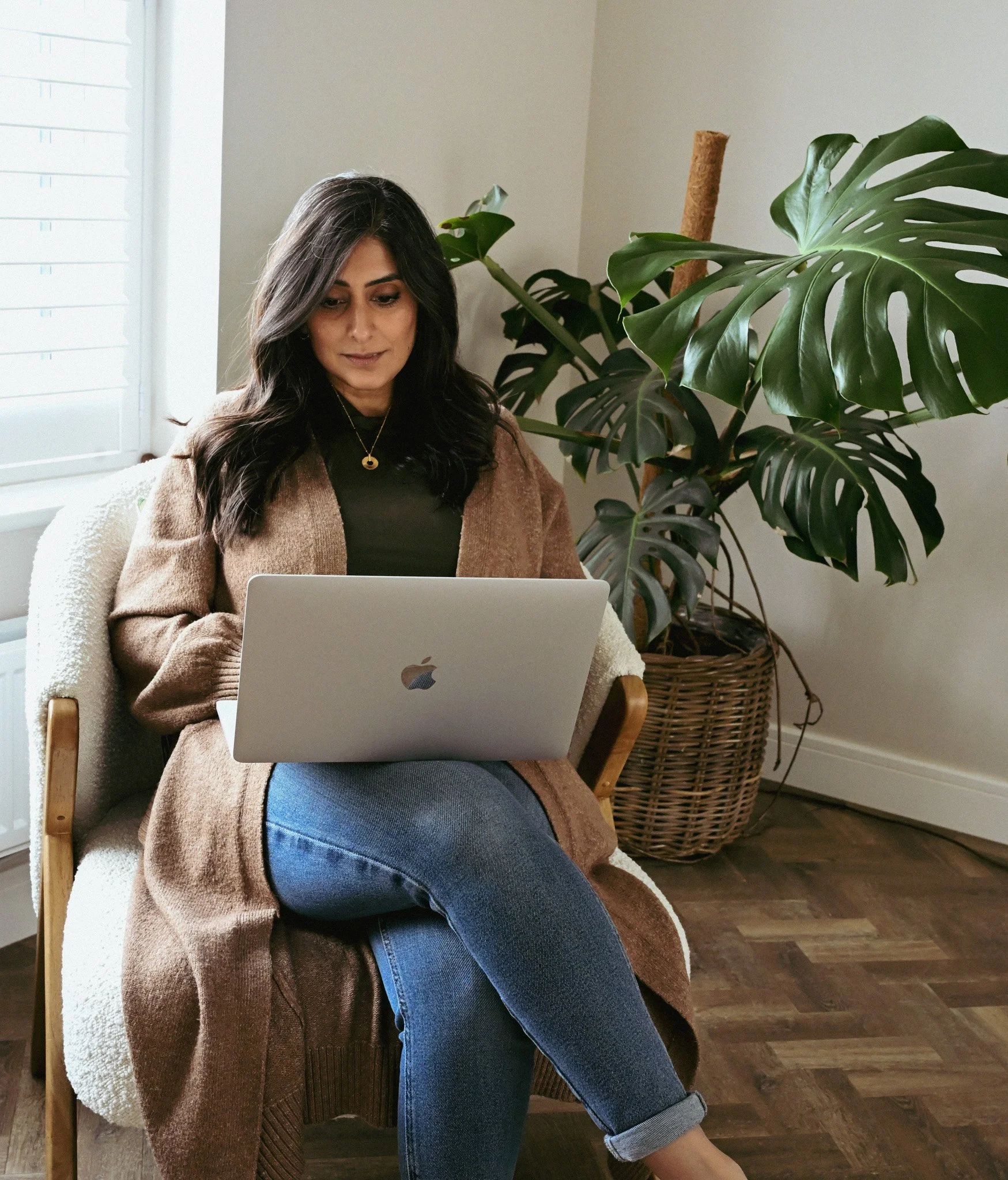 Lady sat working on her laptop with a large plant behind her