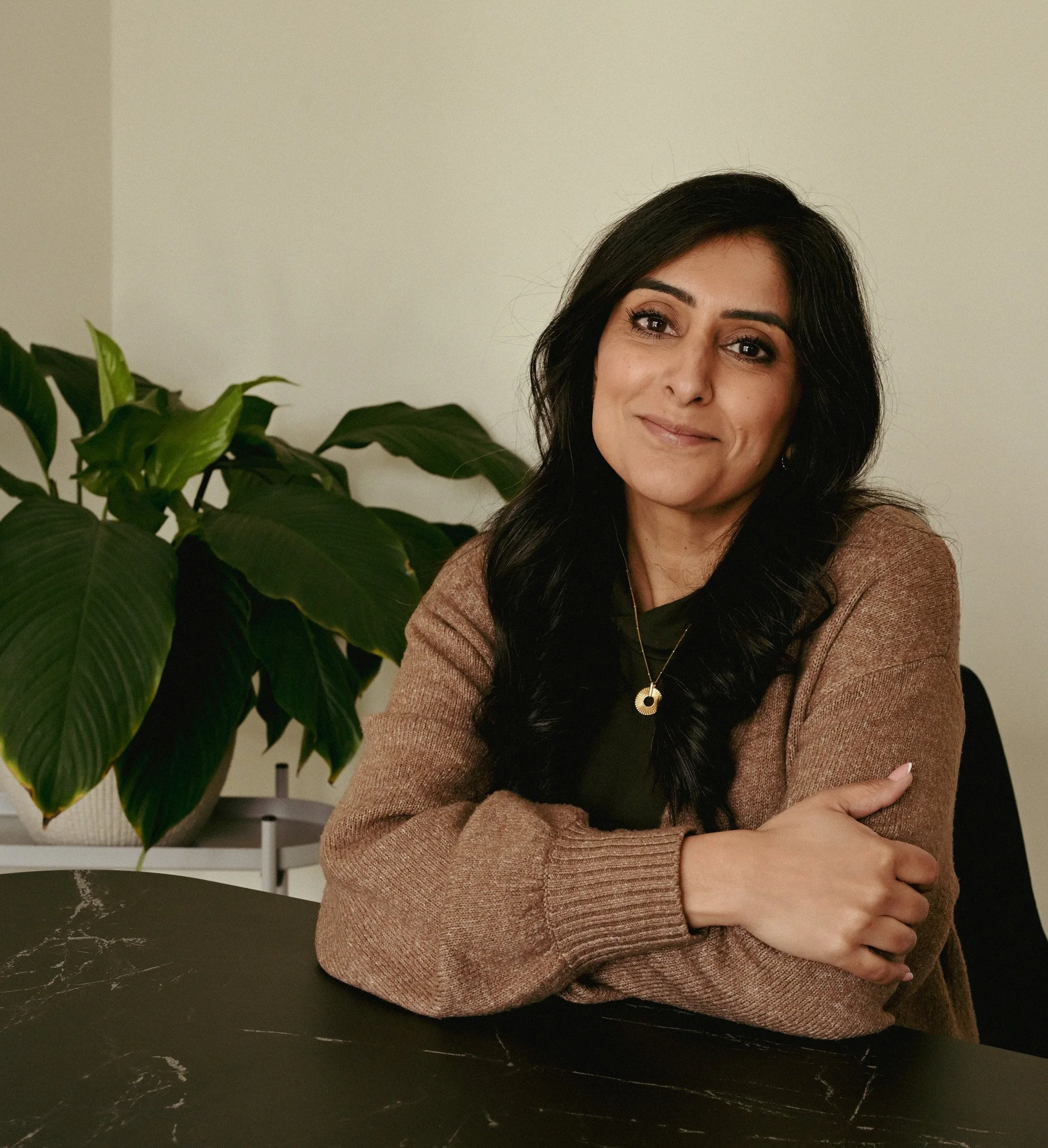 Lady sat smiling at the camera with her arms crossed