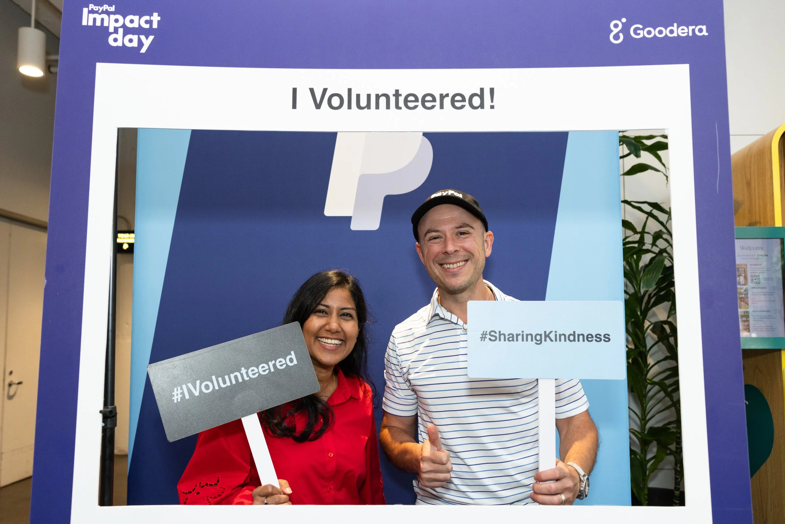 two volunteers smiling holding up signs that say I volunteered and sharing kindness